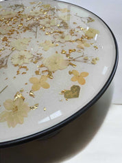 Moderner Epoxidharz Couchtisch mit dekorativer Blütenplatte – natürliche Farbtöne in Creme & Gold, schwarzes Standbein, stabil & pflegeleicht