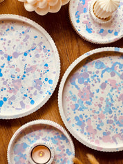 Handgefertigte Keramik-Tabletts in Pastelltönen mit gesprenkeltem Muster, perfekt als Serviertablett oder Dekorationsstück, begleitet von einzigartigen Kerzenhaltern.