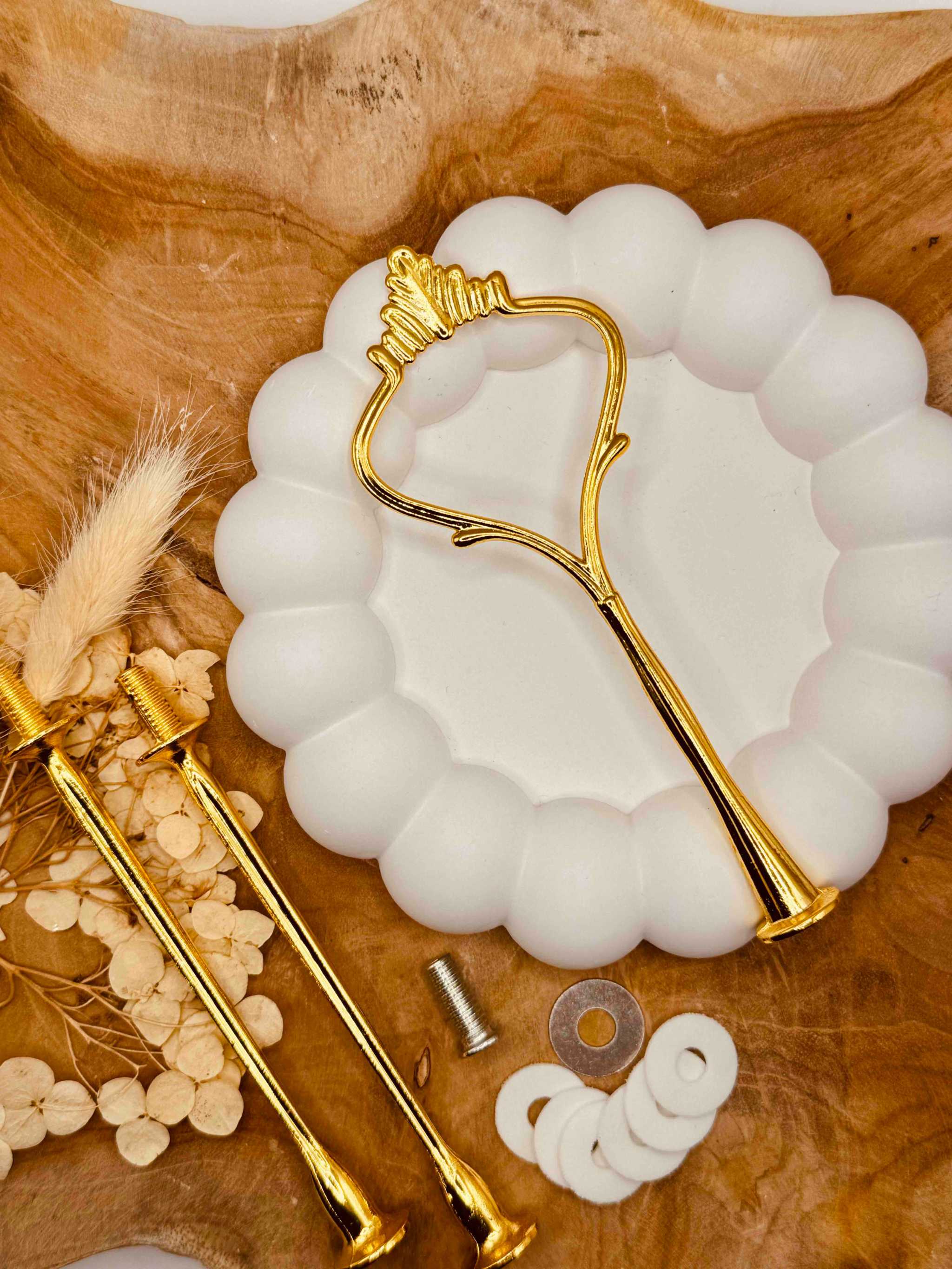 Einzelteile der goldfarbenen Etagerenstange mit Schrauben und Zubehör