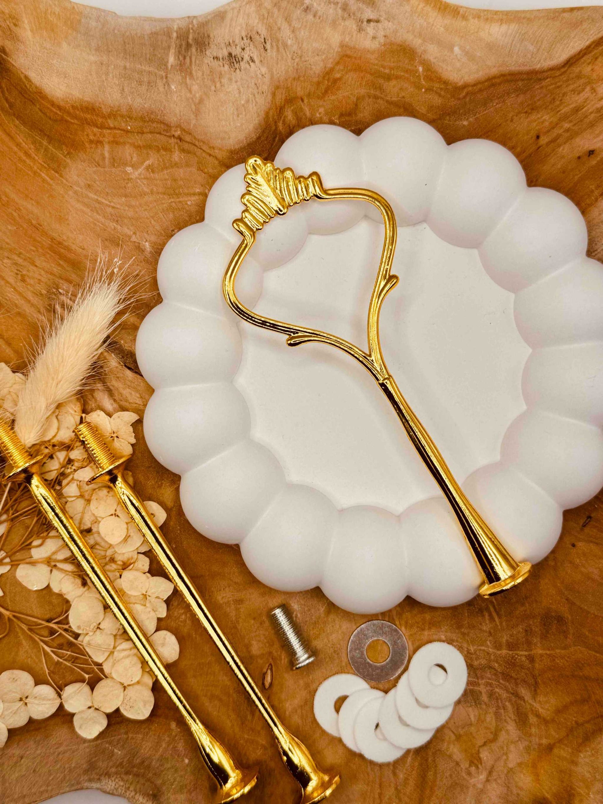 Einzelteile der goldfarbenen Etagerenstange mit Schrauben und Zubehör
