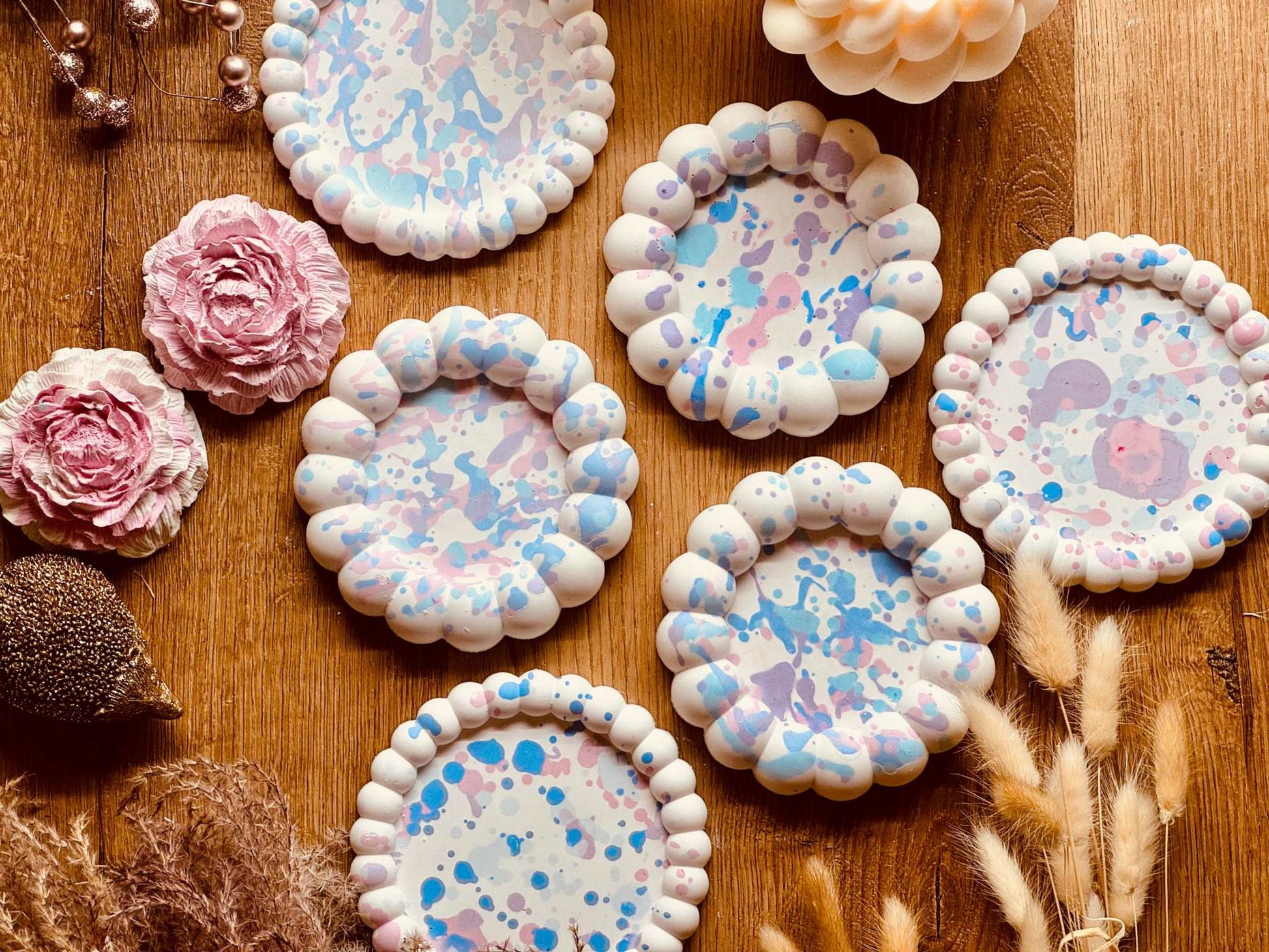 Runde Gießkeramik-Untersetzer mit aufgeblasenem Rand und Spritzmuster in zarten Pastelltönen, handgefertigt und einzeln erhältlich, perfekt für Getränke und Kerzen.