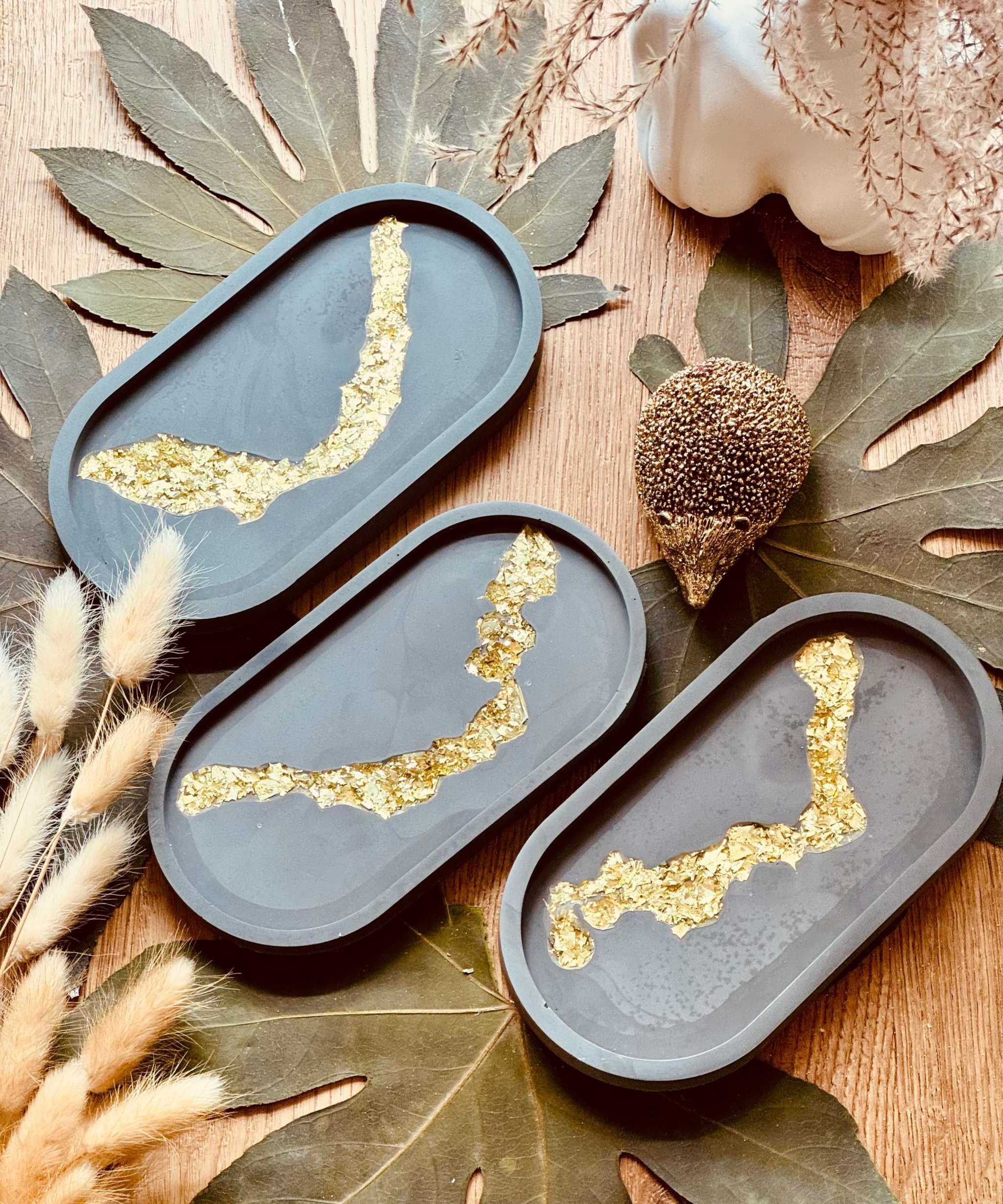Dunkle Gießkeramik Schale mit kunstvollem Blattgold-Resin-Muster, ideal für die stilvolle Präsentation von Schmuck oder anderen kleinen Accessoires.Weisse Deko Schale Giesskeramik mit goldenem Glanz