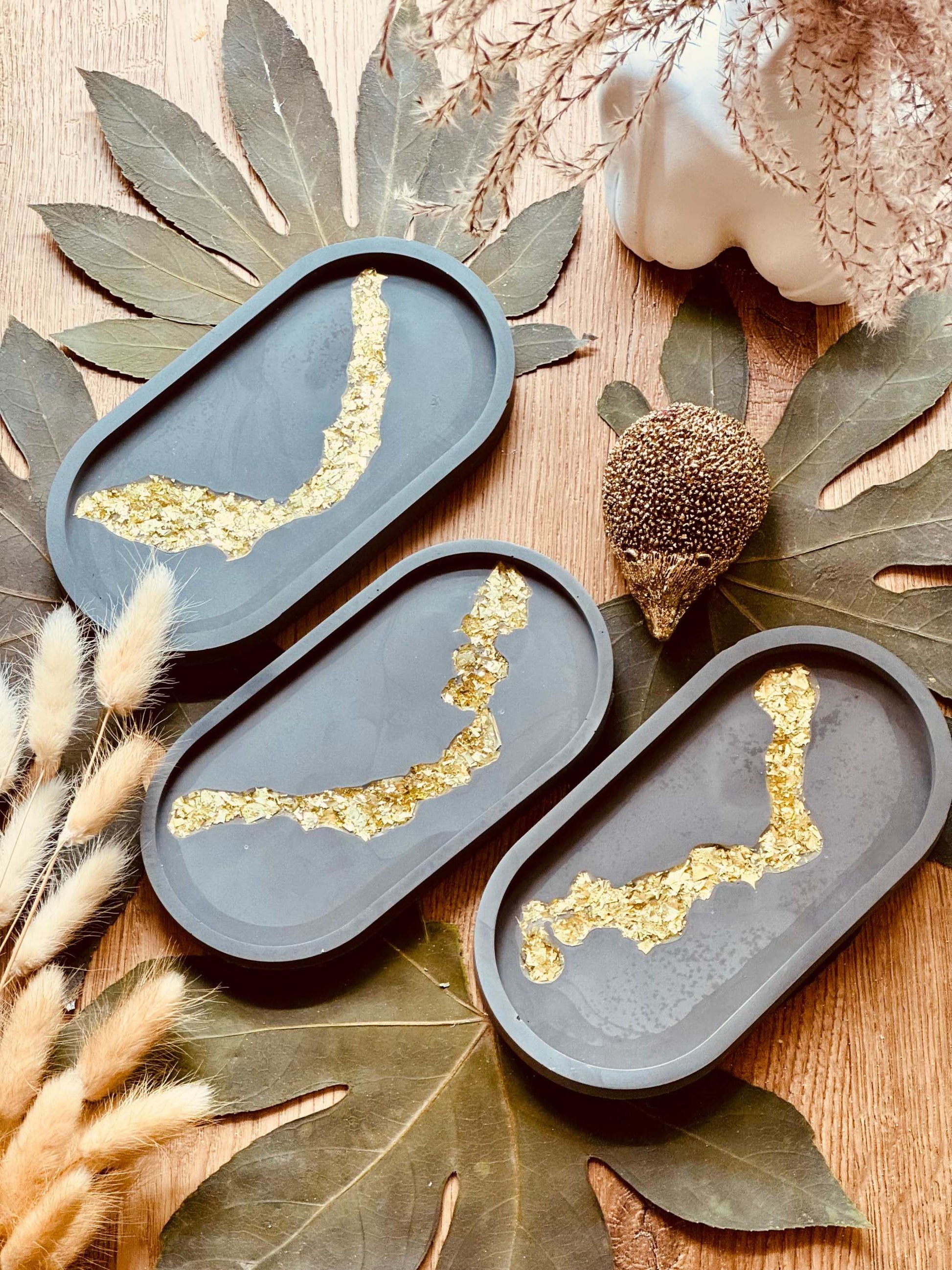 Dunkle Gießkeramik Schale mit kunstvollem Blattgold-Resin-Muster, ideal für die stilvolle Präsentation von Schmuck oder anderen kleinen Accessoires.Weisse Deko Schale Giesskeramik mit goldenem Glanz