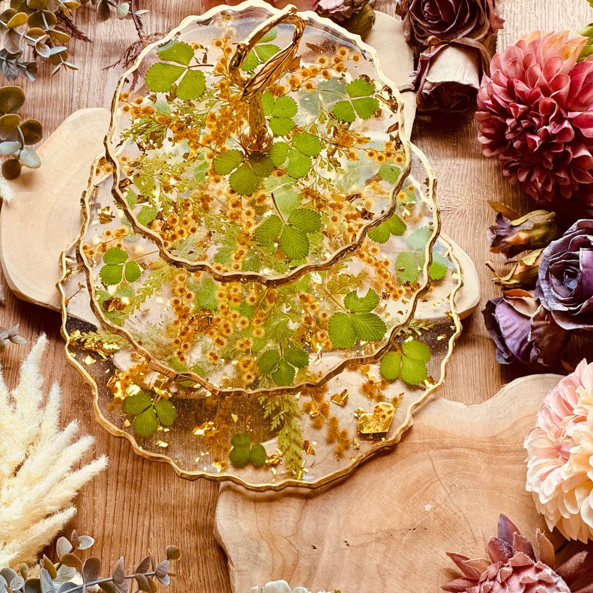 Handgefertigte Epoxidharz Etagere mit Erdbeerblättern, Akazienblüten und Blattgold, 3-stöckig, ideal als dekorative Servierplatte oder Tischdekoration.