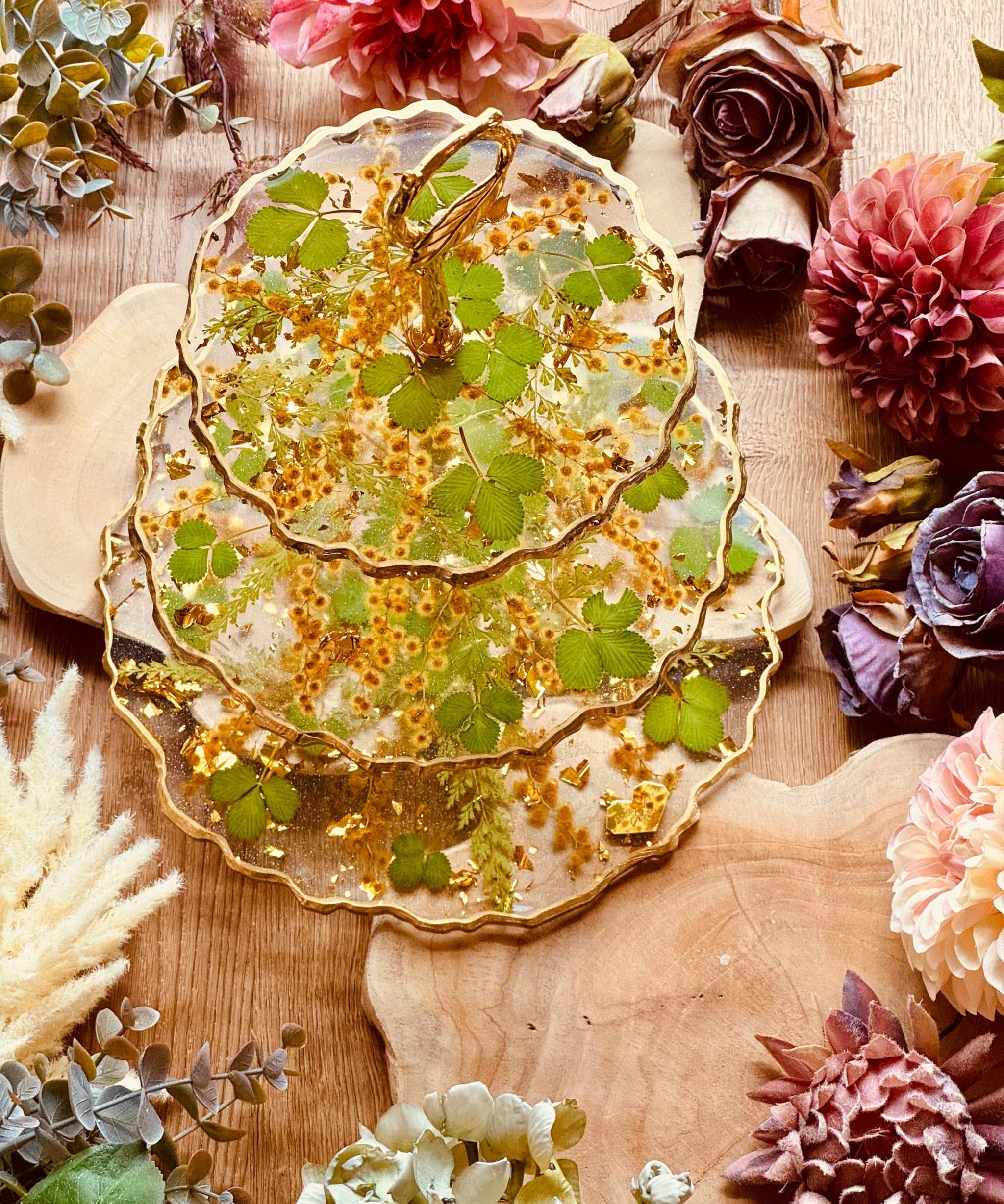 Handgefertigte Epoxidharz Etagere mit Erdbeerblättern, Akazienblüten und Blattgold, 3-stöckig, ideal als dekorative Servierplatte oder Tischdekoration.
