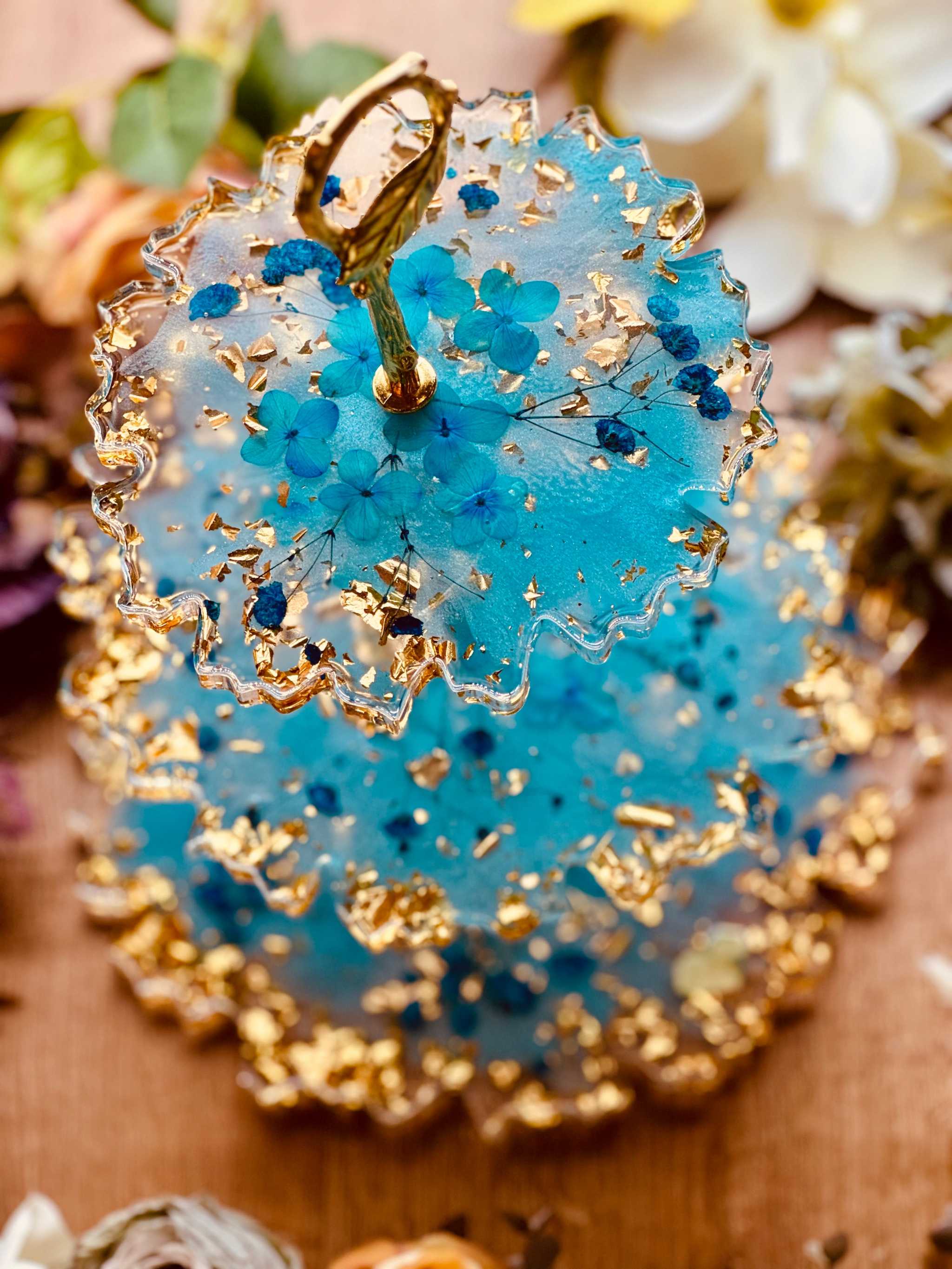 Dekorative 3-stufige Epoxidharz Etagere aus hochwertigem Resin mit Blattgold und Blüten, perfekt für besondere Tischdekorationen und Feiern.