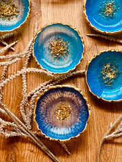 Handgemachte Schmuckschalen aus blauem und türkisem Resin mit goldenen Details auf Holzuntergrund