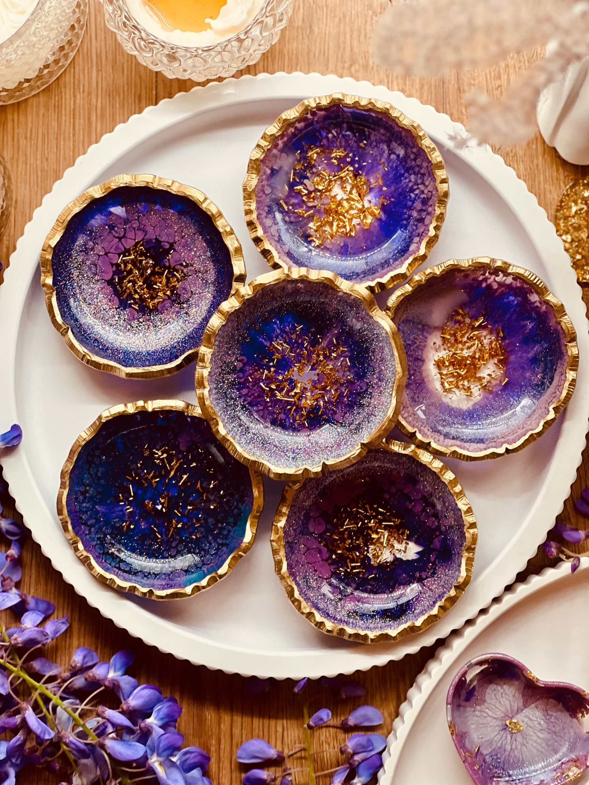 Handgemachte lila Schmuckschalen aus Resin mit goldenen Details auf weißem Teller
