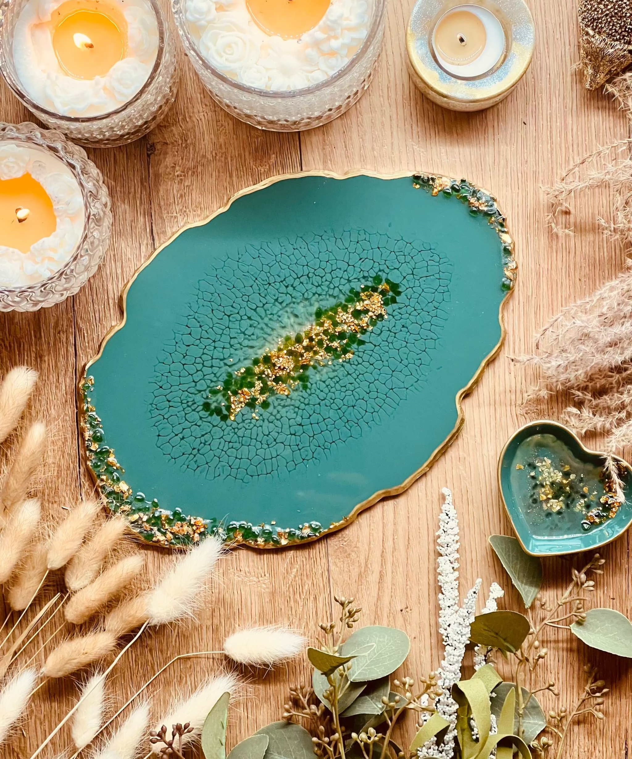 Grünes handgemachtes Resin Tablett mit goldenen Details und glitzernden Dekosteinen auf Holztisch mit Kerzen und Trockenblumen