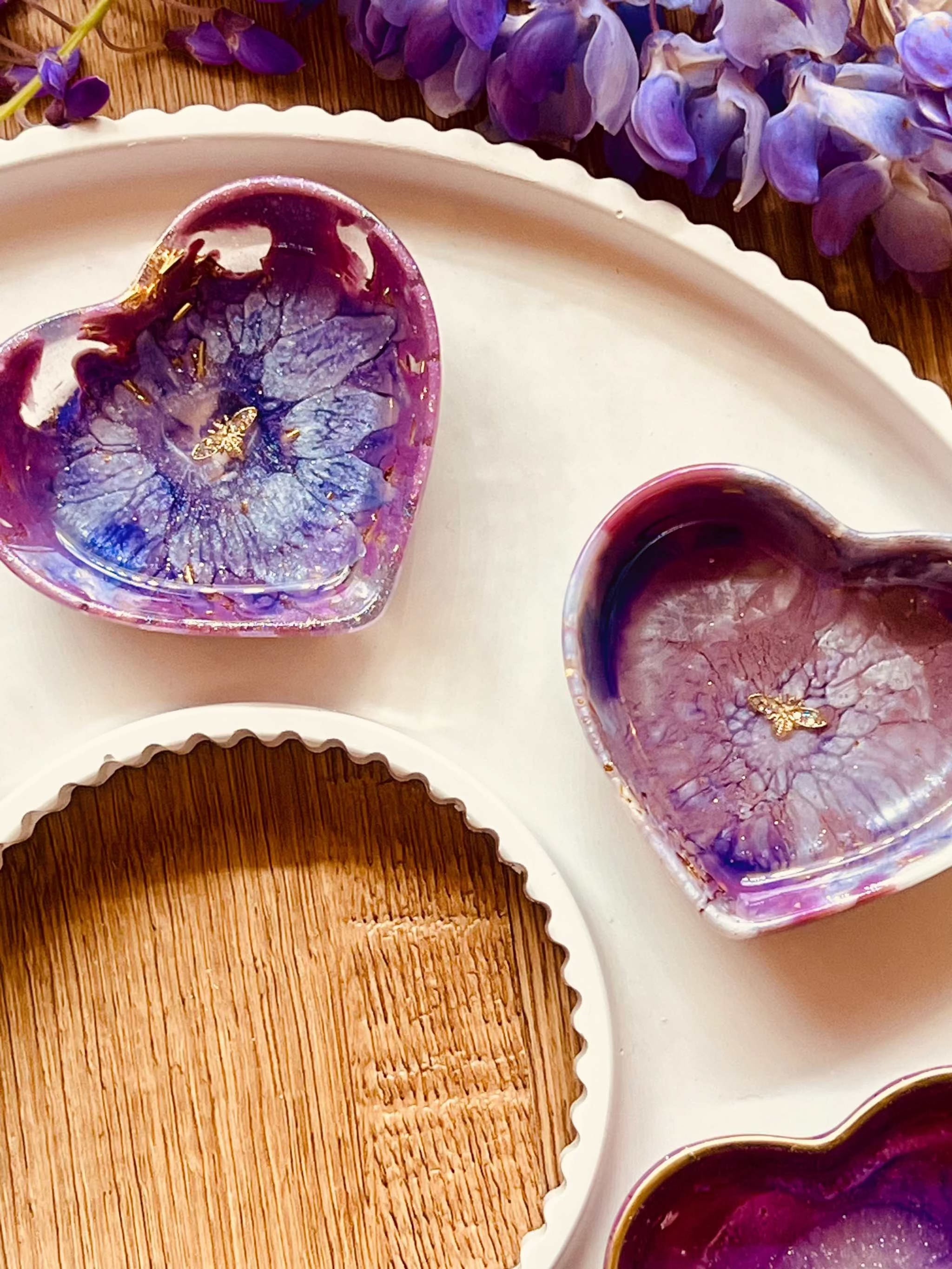 Handgemachte lila Schmuckschalen aus Resin mit goldenen Details und floralen Mustern in Herzform auf weißem Tablett