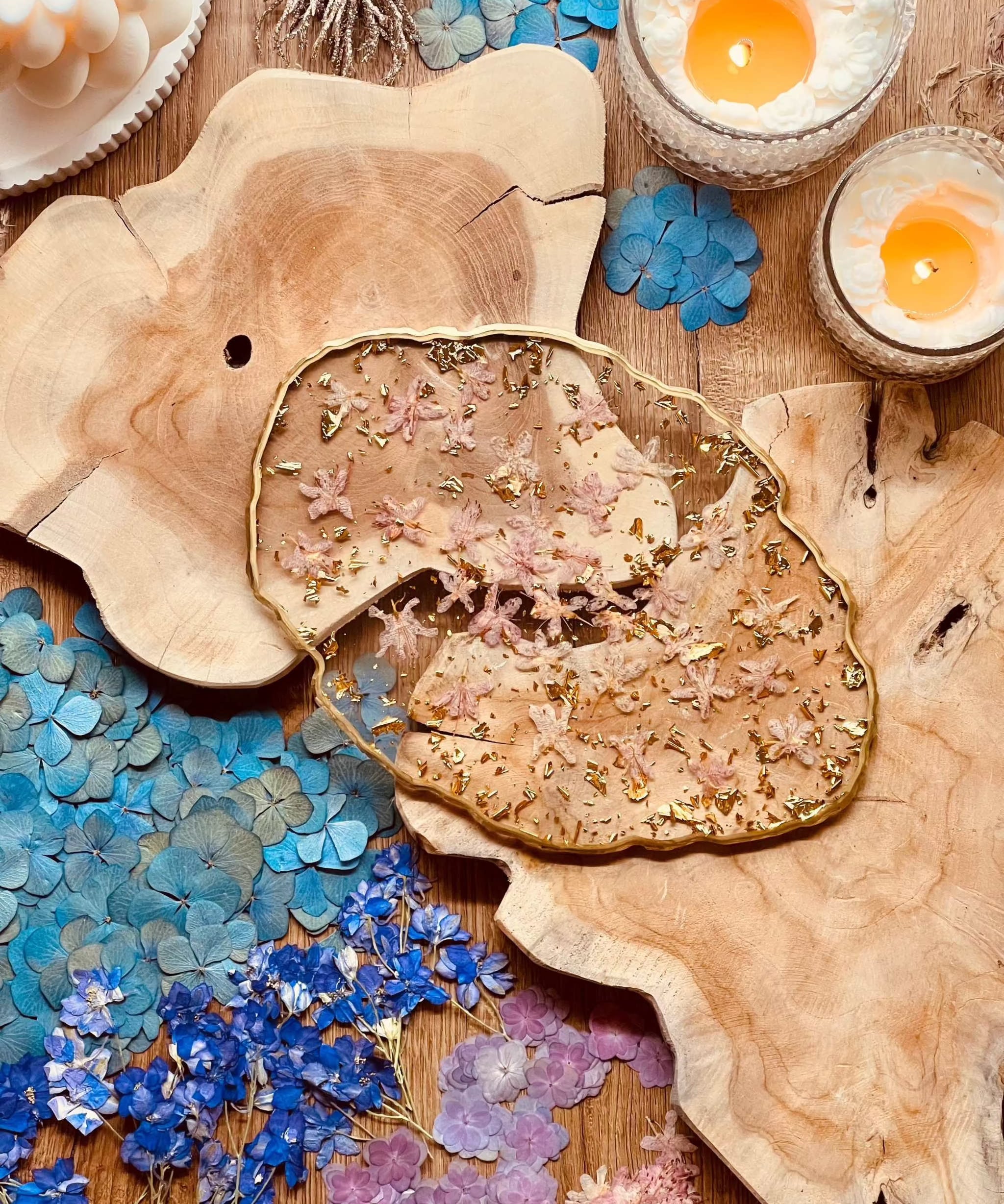 Handgemachtes Tablett aus Resin mit rosa Rhododendronblüten und goldenen Details auf Holzuntergrund mit Kerzen und getrockneten Blüten