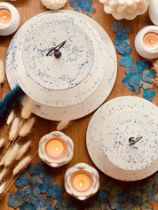 White ceramic tiered stand with sparkling highlights surrounded by candles and decorative elements.