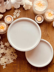 Modern ceramic tiered tray with stripe design on wooden table surrounded by candles for versatile decor.