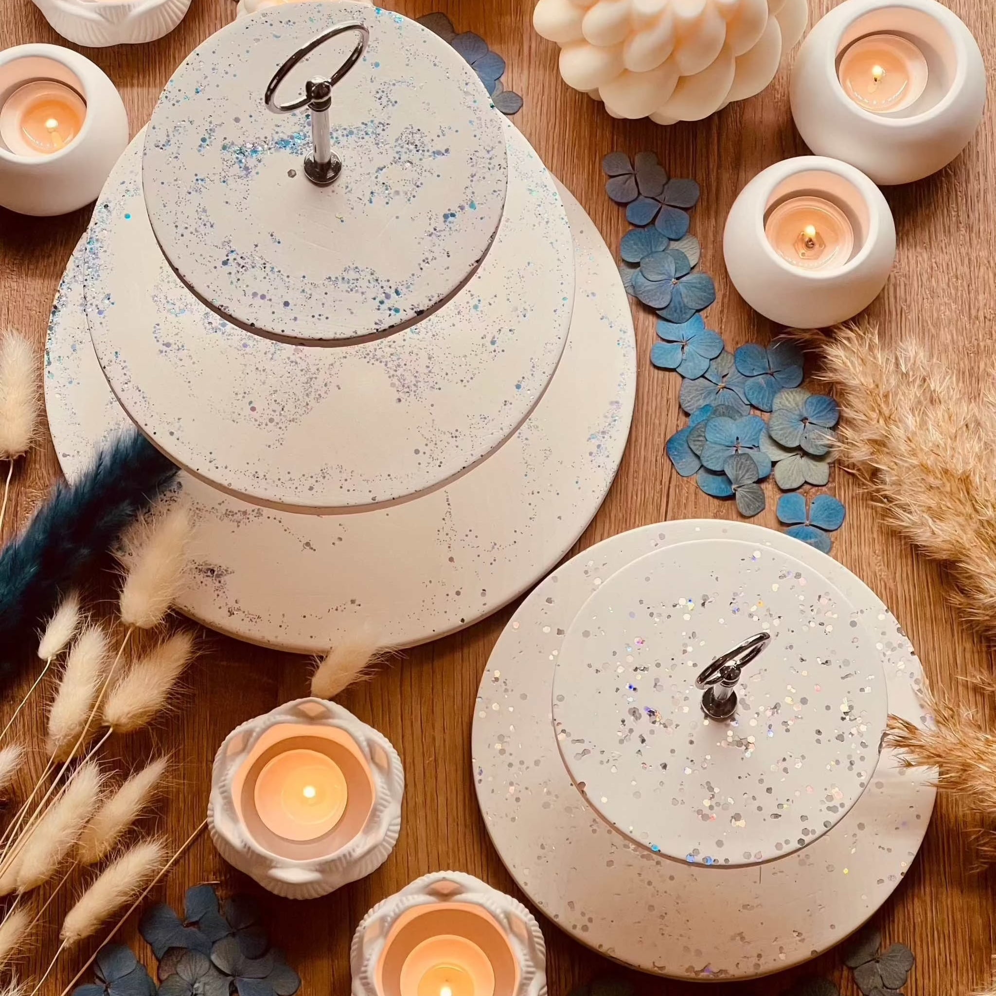 White Gießkeramik tiered stand with sparkling highlights, surrounded by candles and decor in two sizes.Giesskeramik weisse Deko Etagere mit Glanzdetails