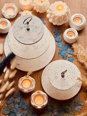 White Gießkeramik tiered stand with sparkling highlights, surrounded by candles and decor in two sizes.Giesskeramik weisse Deko Etagere mit Glanzdetails