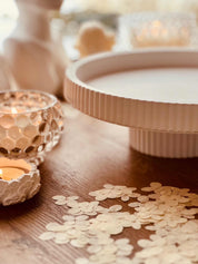 Modern Gießkeramik Etagere with striped design on a wooden table decorated with candles and confetti.