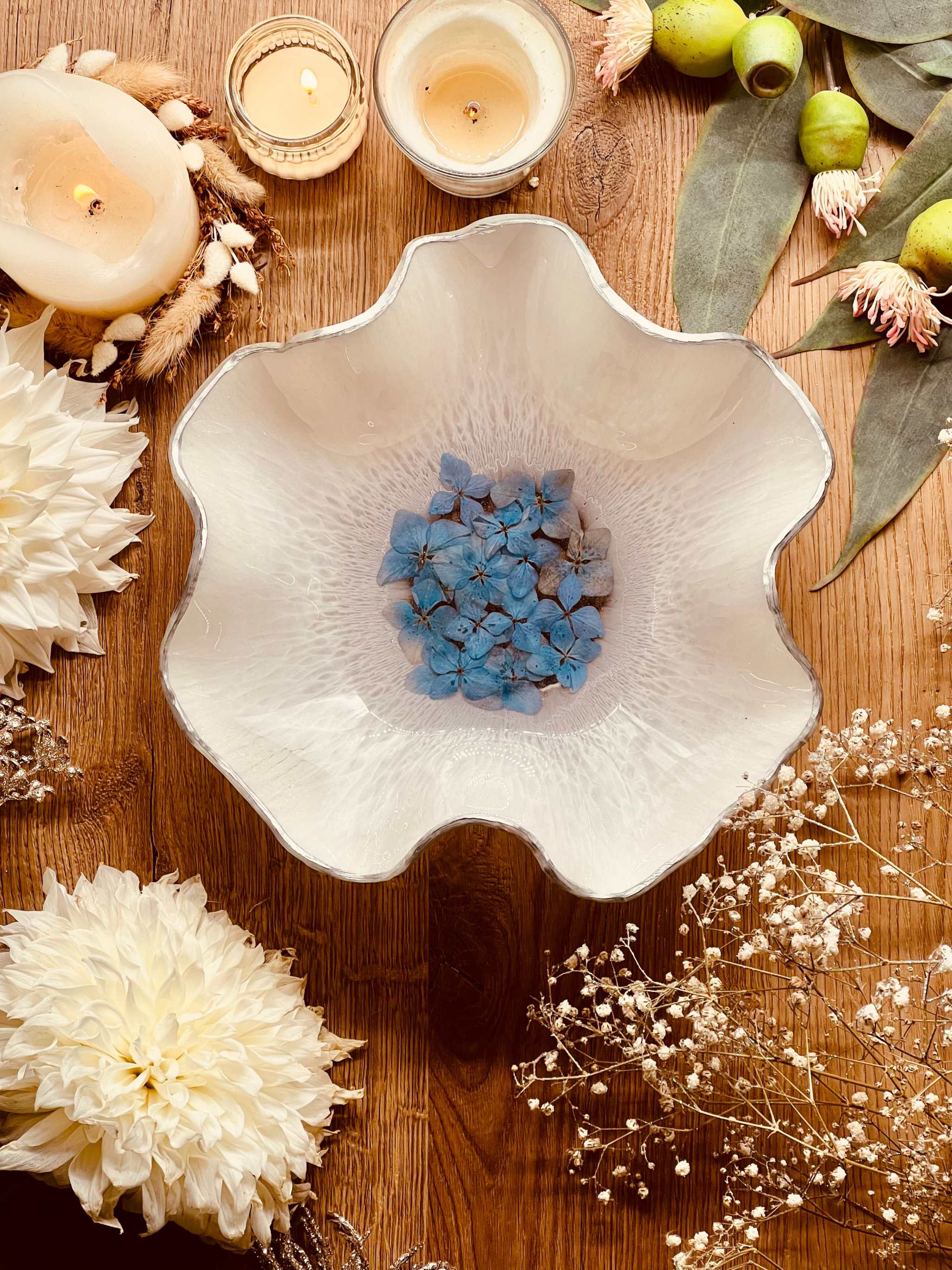 handgemachte weiße Schale aus Resin mit silbernen Details und getrockneten blauen Hortensien auf Holztisch dekoriert