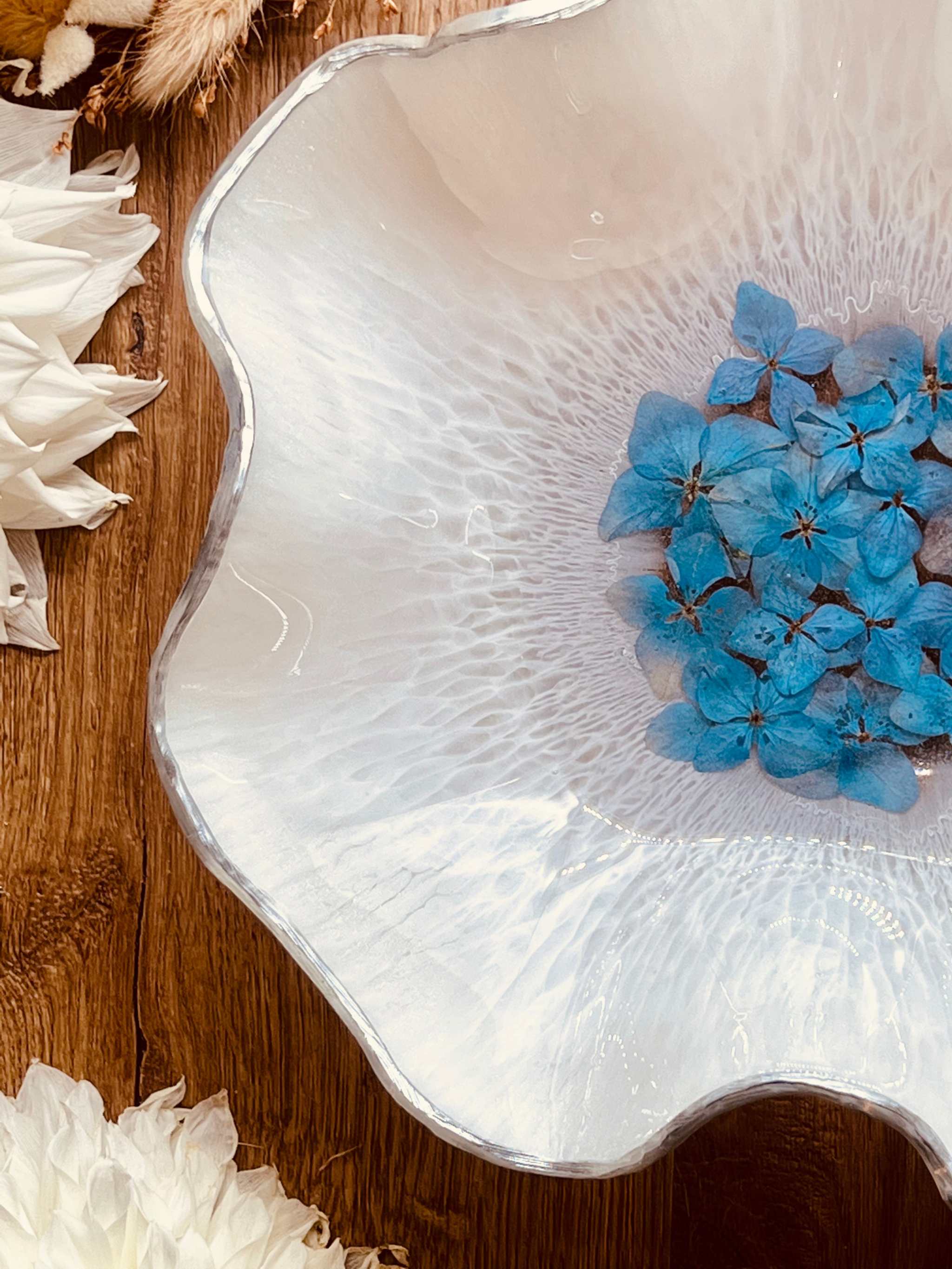 Handgemachte Schale aus weißem Resin mit silbernen Akzenten und blauen Hortensien als Dekoration