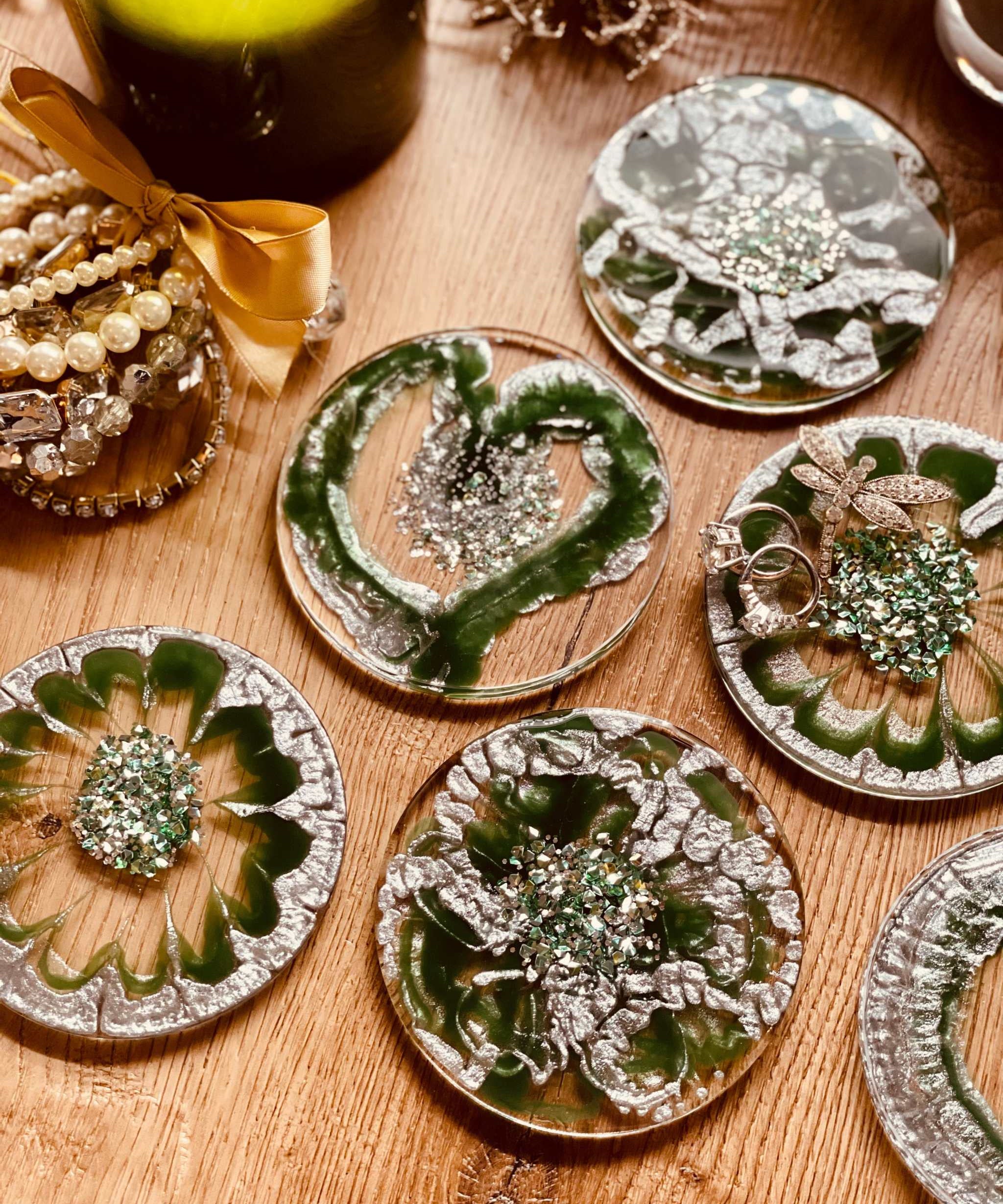 8 handgemachte grüne Resin Untersetzer mit silbernen Details auf Holztisch