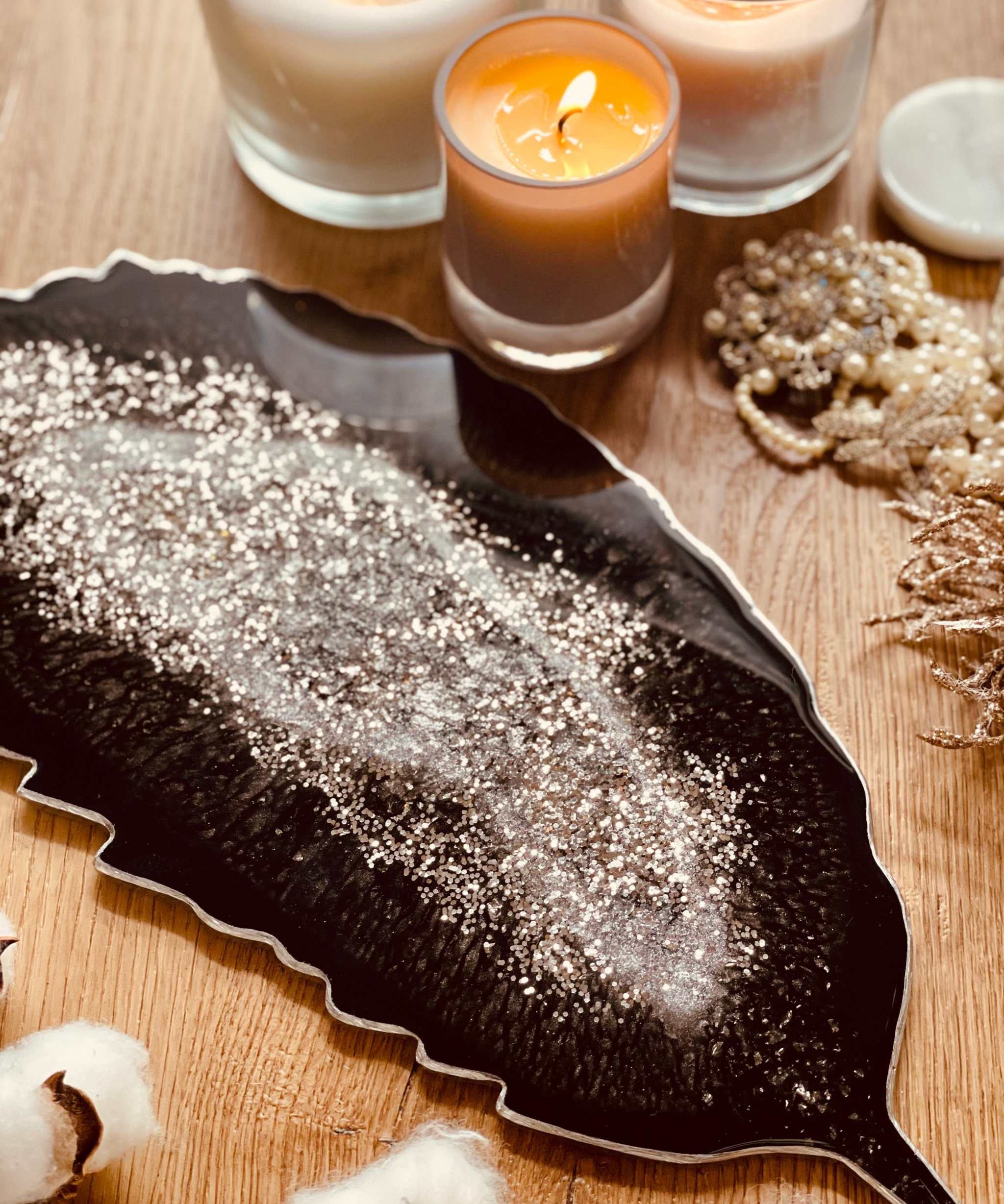 Schwarzes handgemachtes Feder Tablett aus Resin mit silbernen Details und Kerzen auf Holztisch