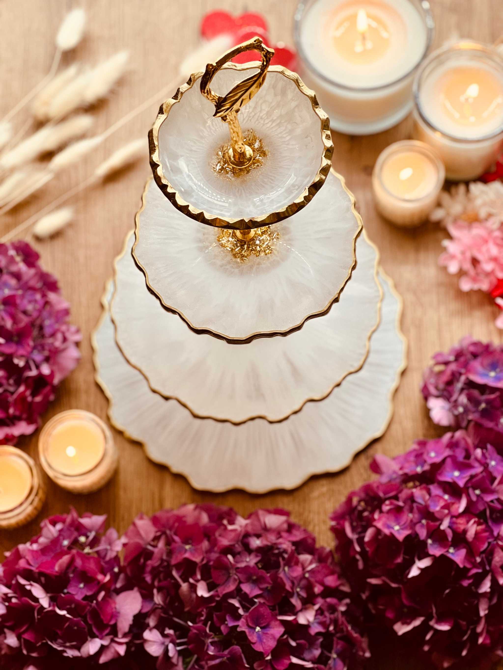 Vierstöckige Etagere aus Resin mit goldenen Rändern, handgemacht und dekorativ auf einem Holztisch mit Kerzen und Blumen