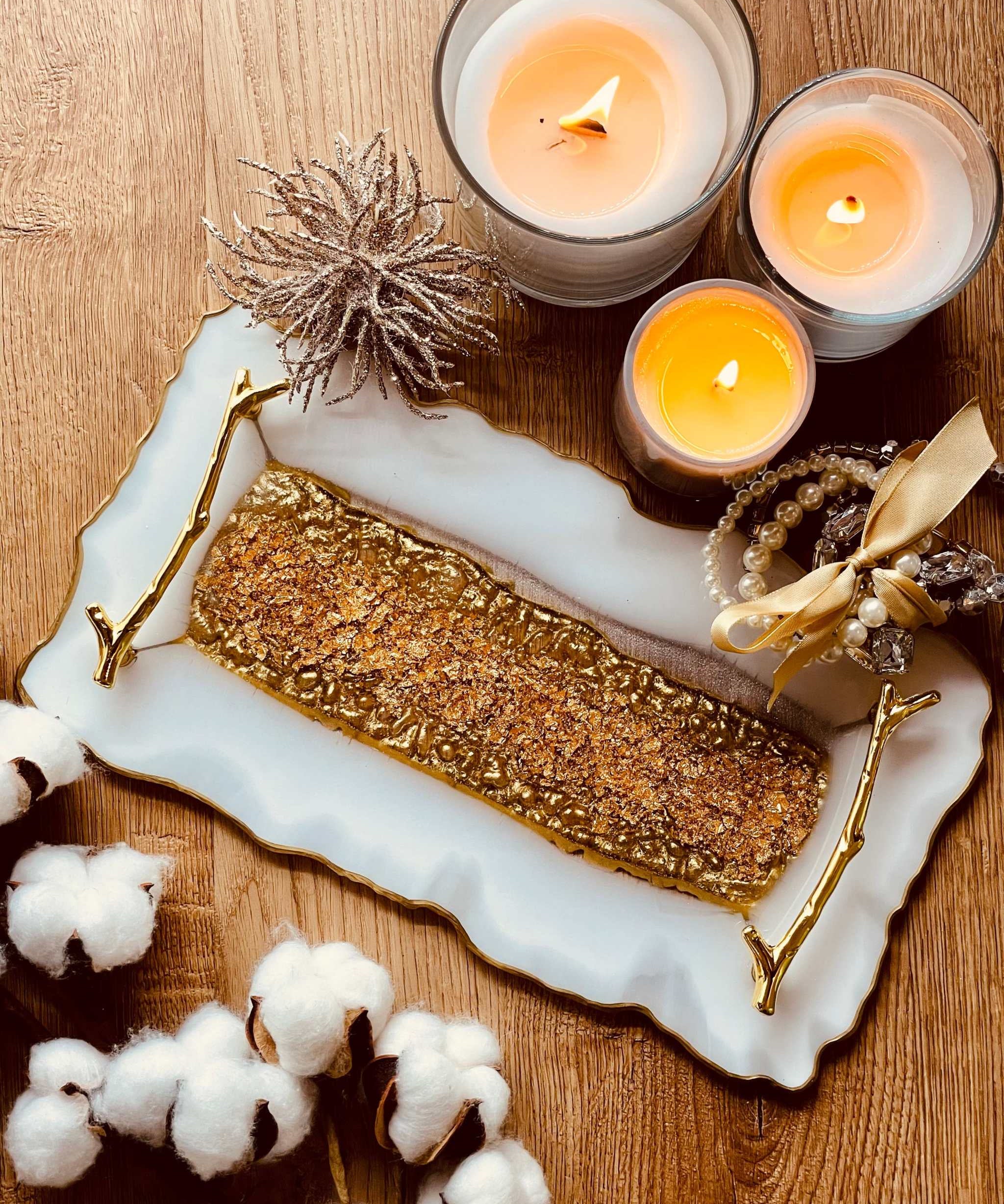 Tablett aus Resin mit goldenen Griffen, dekoriert mit Kerzen und Schmuck auf Holztisch