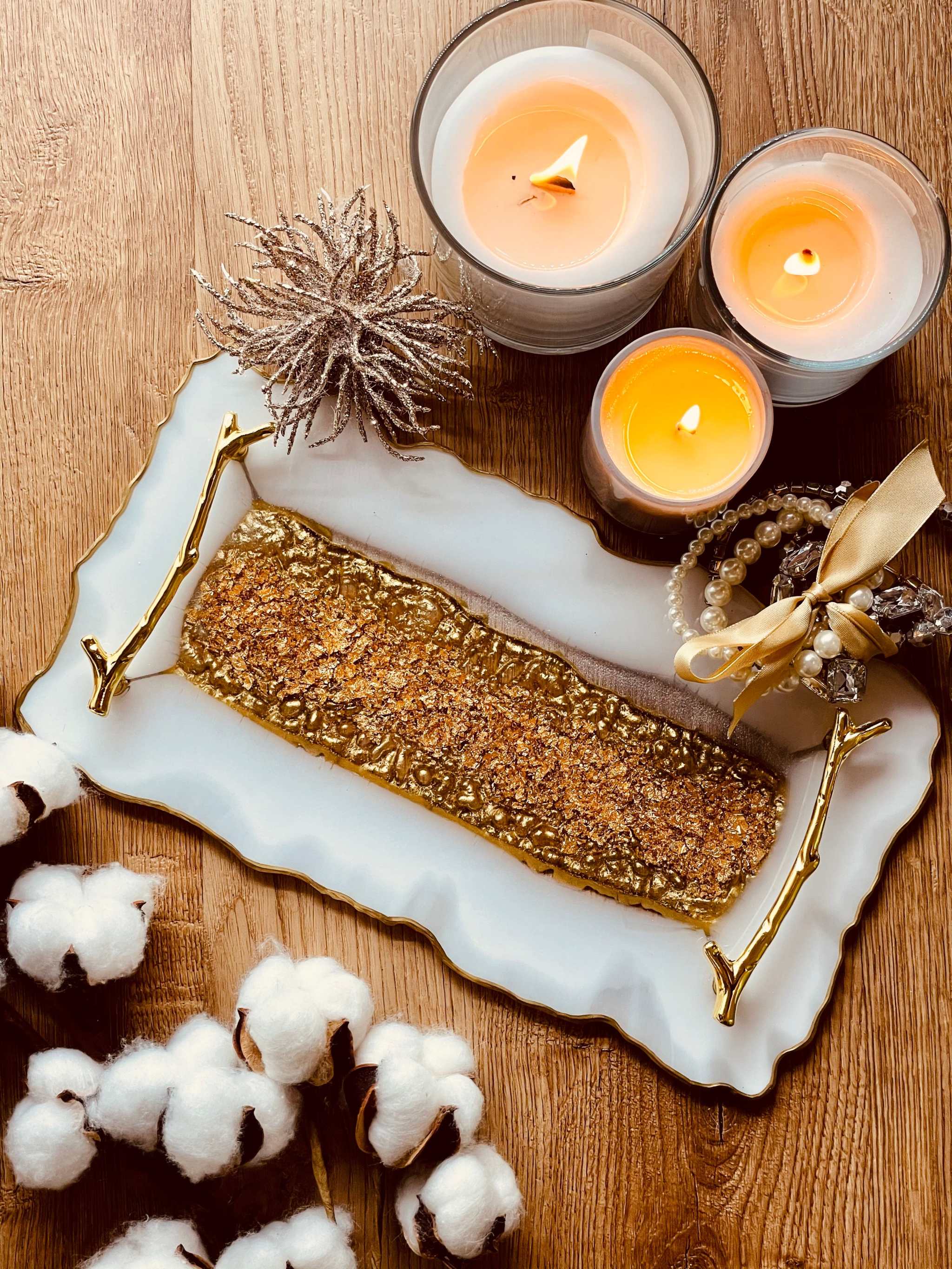 Tablett aus Resin mit goldenen Griffen, dekoriert mit Kerzen und Schmuck auf Holztisch