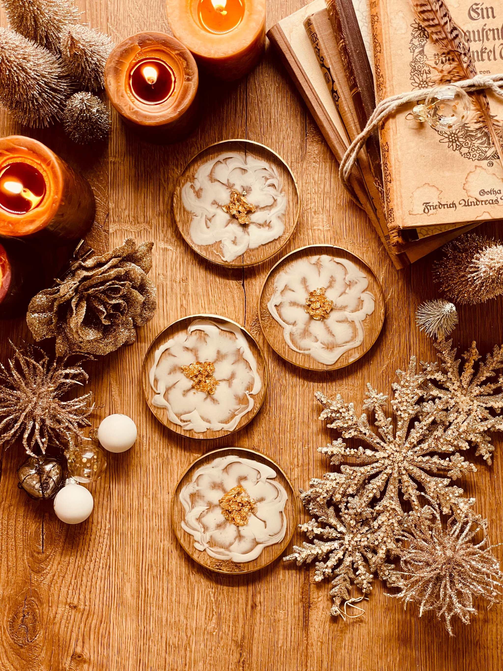 4 exklusive Untersetzer aus weißem Resin mit goldenen Details auf Holzoberfläche neben Kerzen und Weihnachtsdekoration