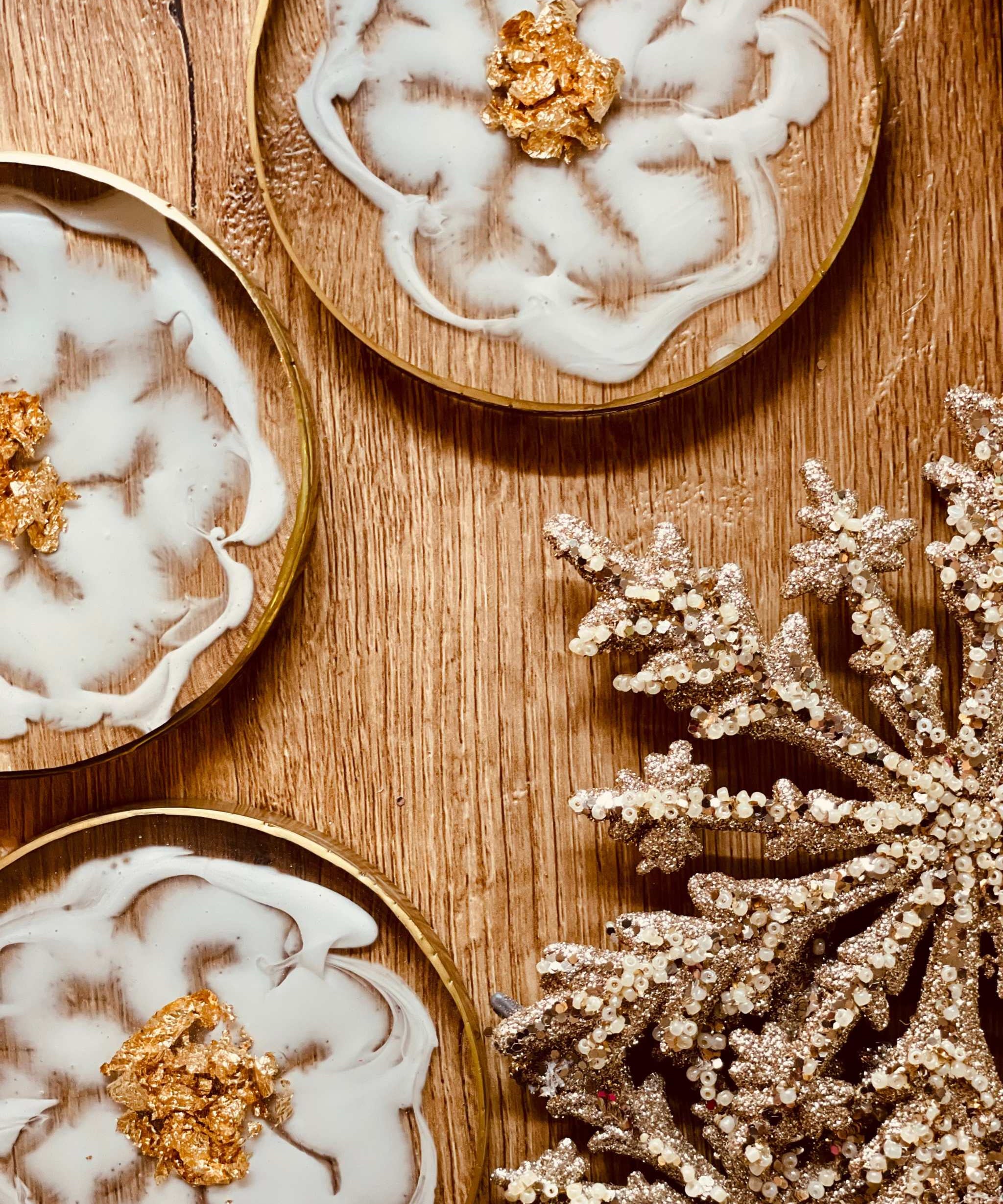 4 exklusive handgemachte weiße Resin-Untersetzer mit goldenen Details auf Holztisch