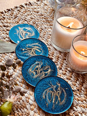 4 Untersetzer aus Resin in Blau mit goldenen Details handgemacht auf geflochtenem Tischläufer mit brennenden Kerzen