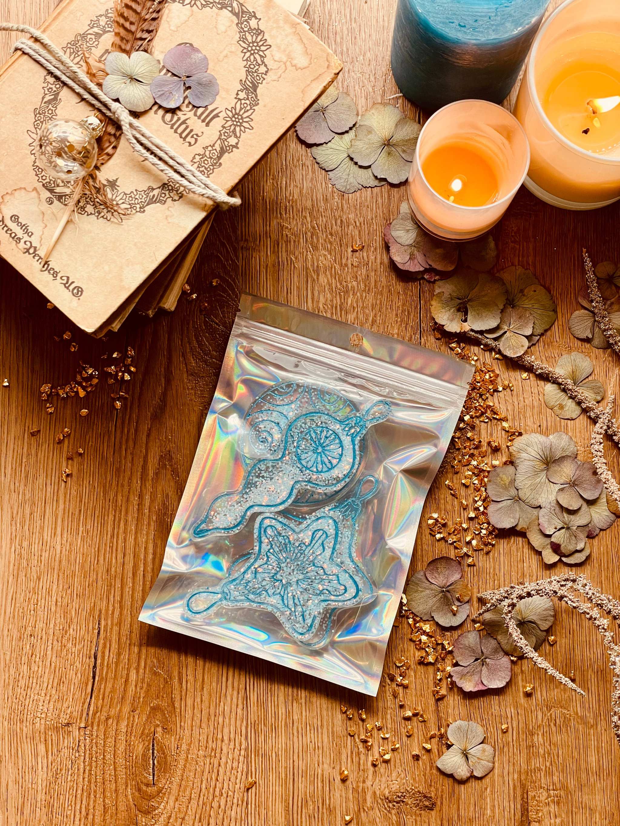 Handmade turquoise and silver resin Christmas tree ornaments set of four on a wooden table with candles.