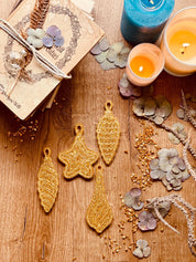 Goldene handgemachte Weihnachtsbaumanhänger aus Resin im 4-teiligen Set auf Holztisch mit Kerzen und Trockenblumen
