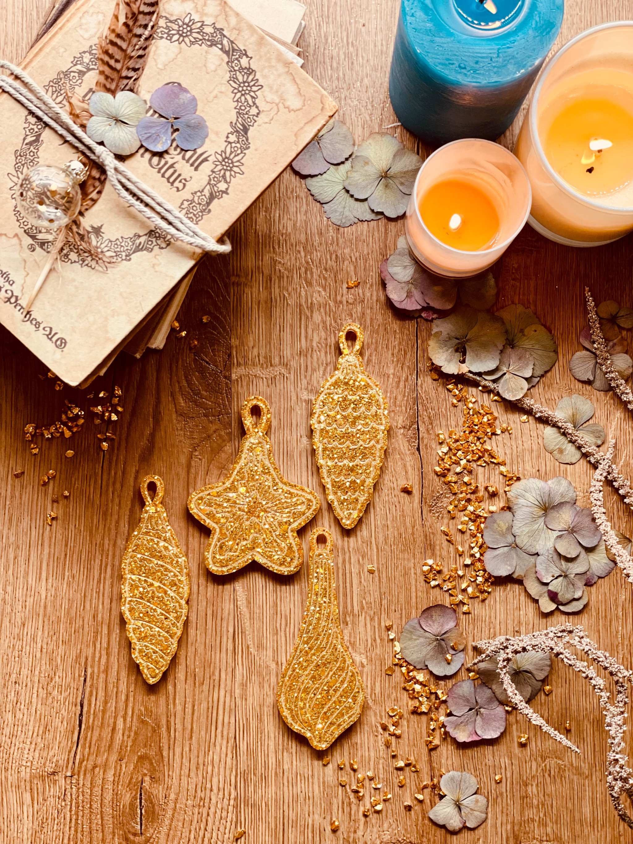Goldene handgemachte Weihnachtsbaumanhänger aus Resin im 4-teiligen Set auf Holztisch mit Kerzen und Trockenblumen