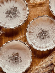 handgemachte schneeweiße Schmuckschalen aus Resin mit silbernen Details und gewelltem Rand auf Holztisch