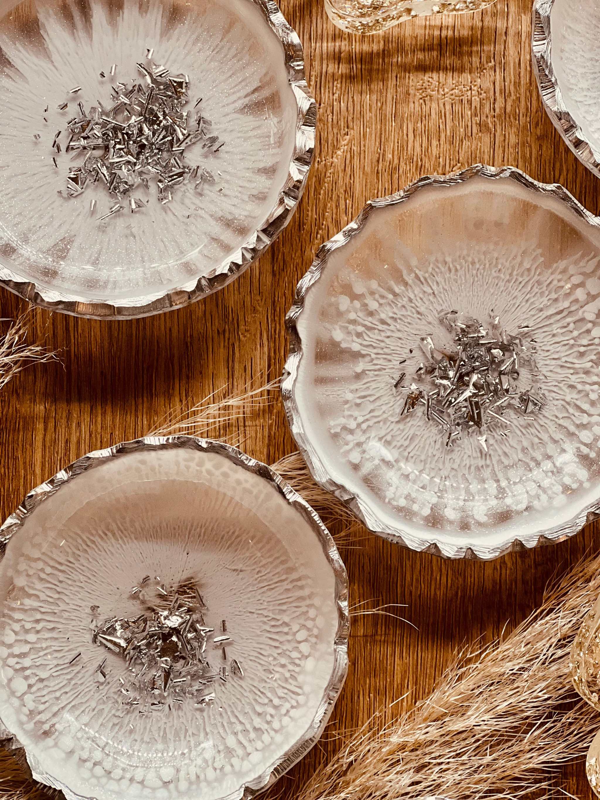 handgemachte schneeweiße Schmuckschalen aus Resin mit silbernen Details und gewelltem Rand auf Holztisch