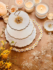 dreistöckige handgemachte Resin Etagere mit goldfarbenem Rand dekoriert auf Holztisch mit Kerzen und Blumen