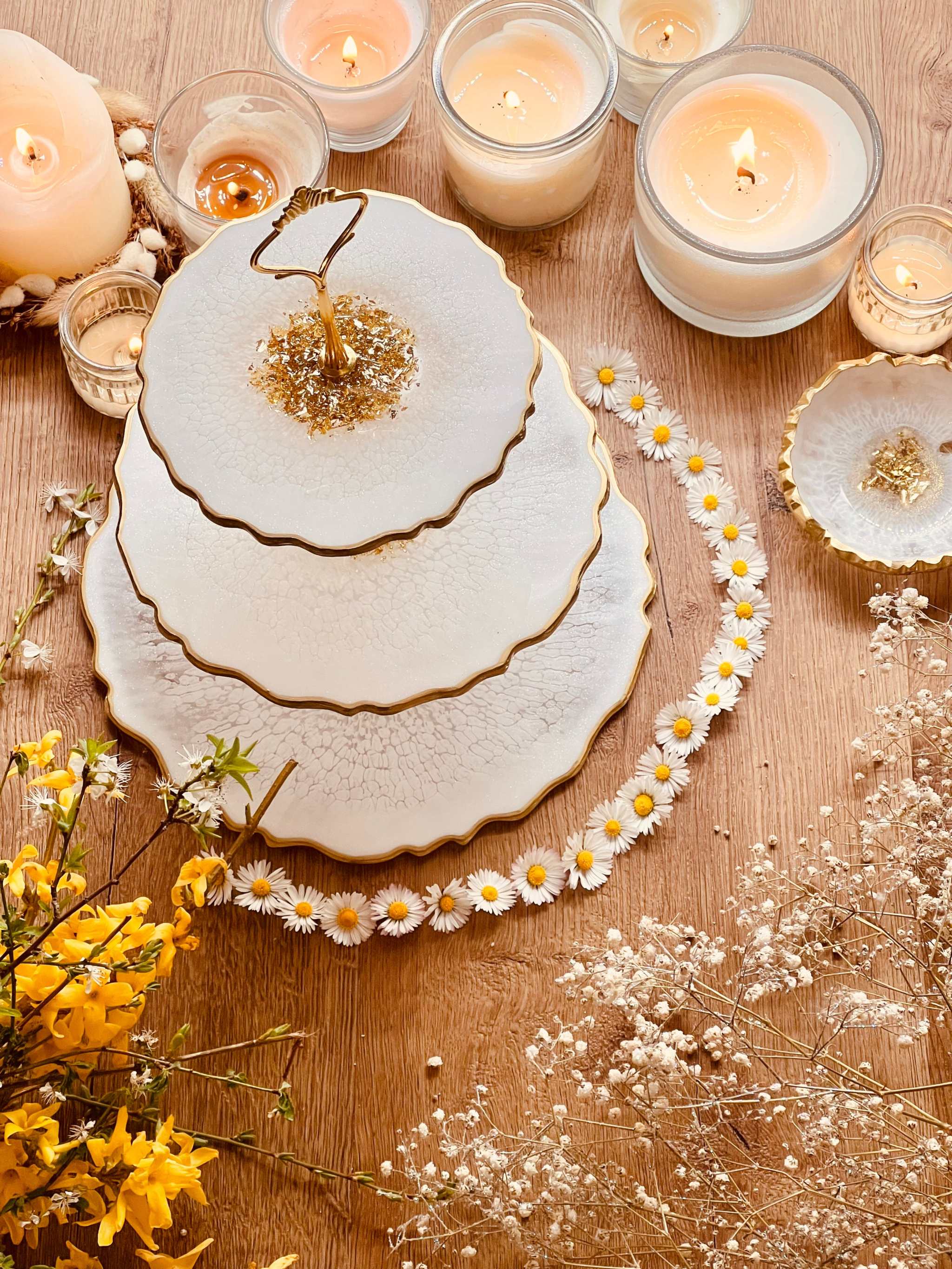 dreistöckige handgemachte Resin Etagere mit goldfarbenem Rand dekoriert auf Holztisch mit Kerzen und Blumen