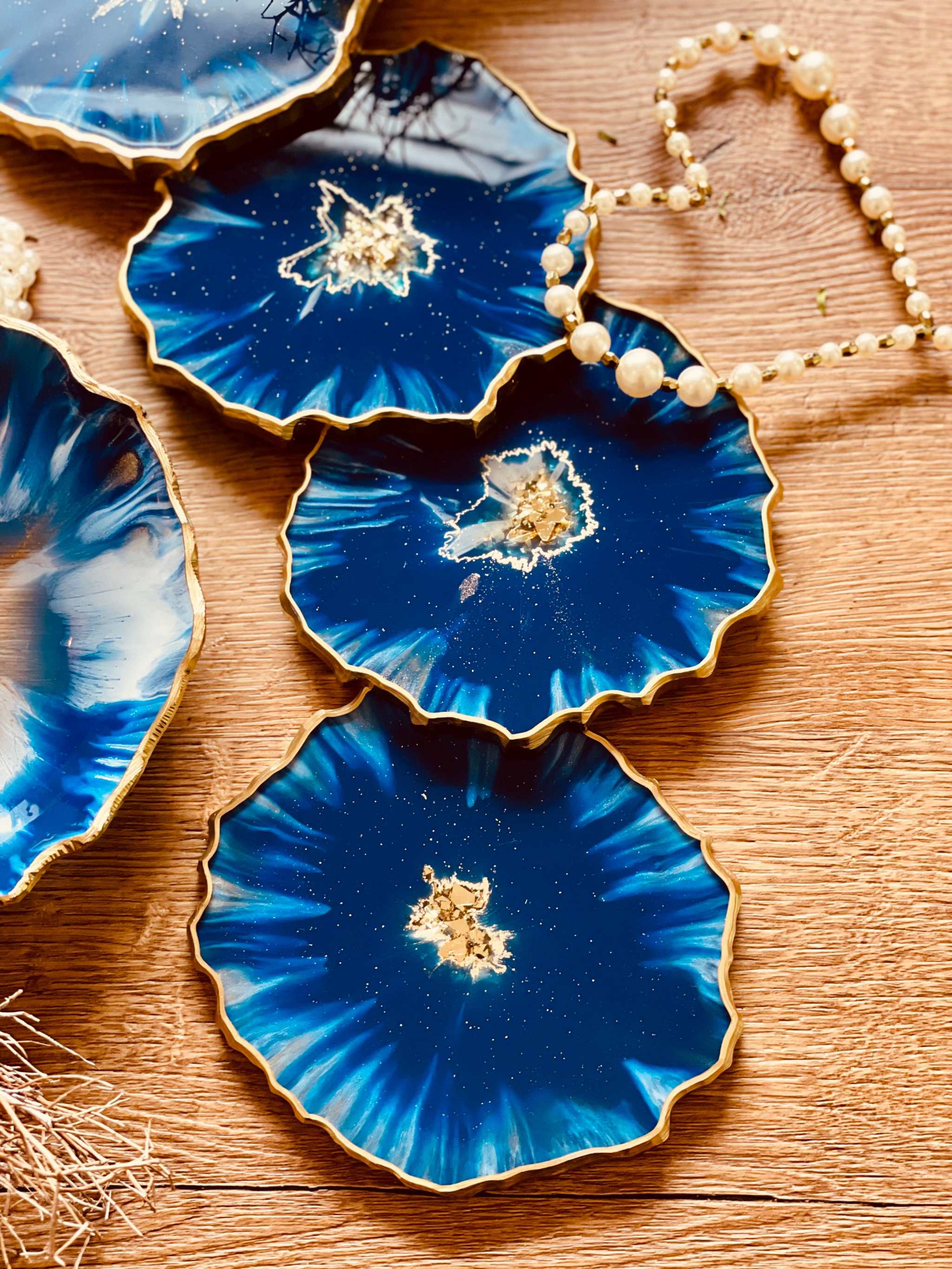 4 Untersetzer aus Resin in Blau mit goldenen Details auf Holztisch handgemacht einzigartig