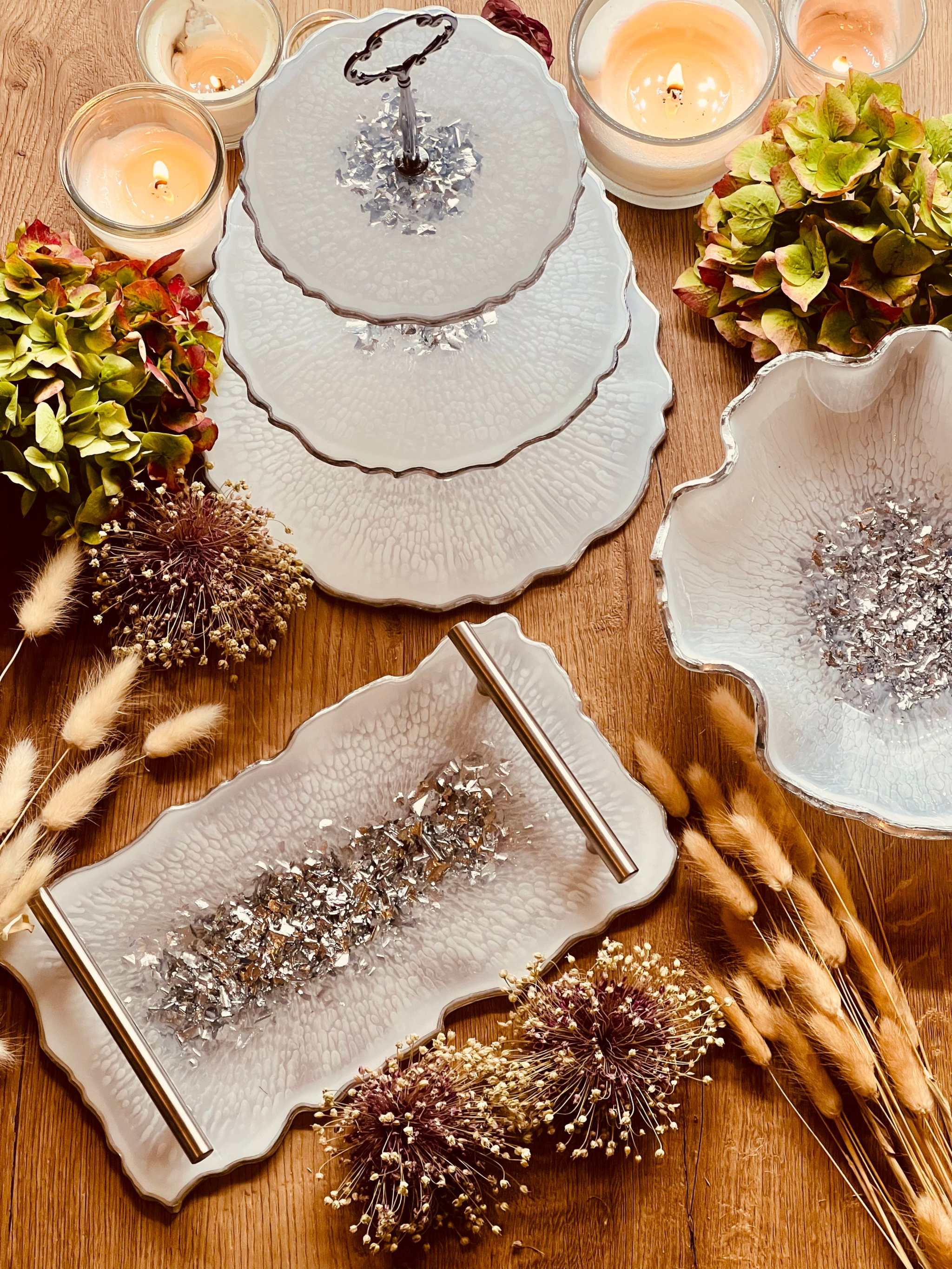 Handgemachte individuelle Deko Sets aus Resin mit unregelmäßigen, geschwungenen Formen auf Holztisch mit Kerzen und Trockenblumenarrangements