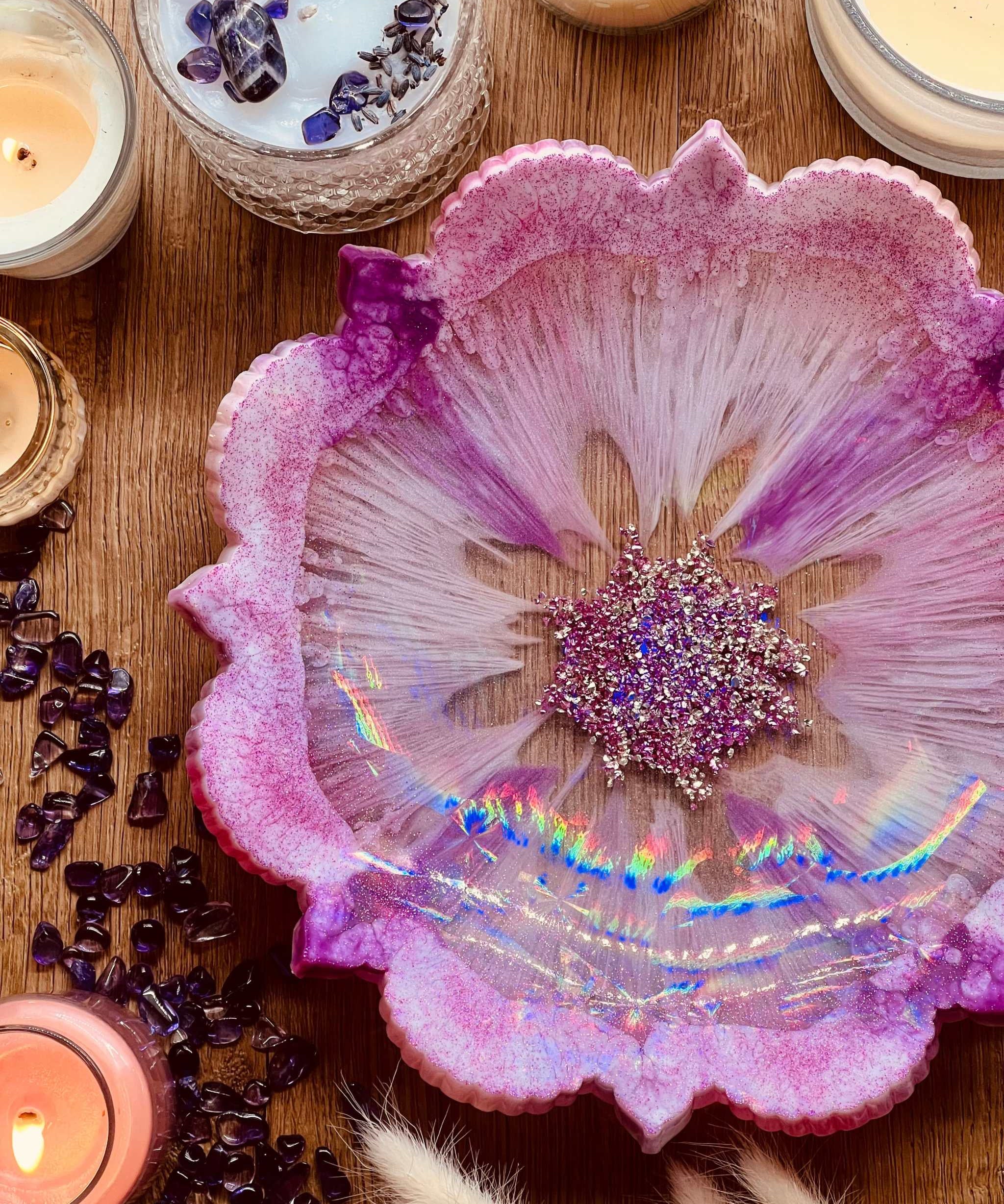 Handgemachte pinke Resin Schale mit silbernen Details und holographischer Oberfläche auf Holztisch mit Kerzen und Amethyststeinen