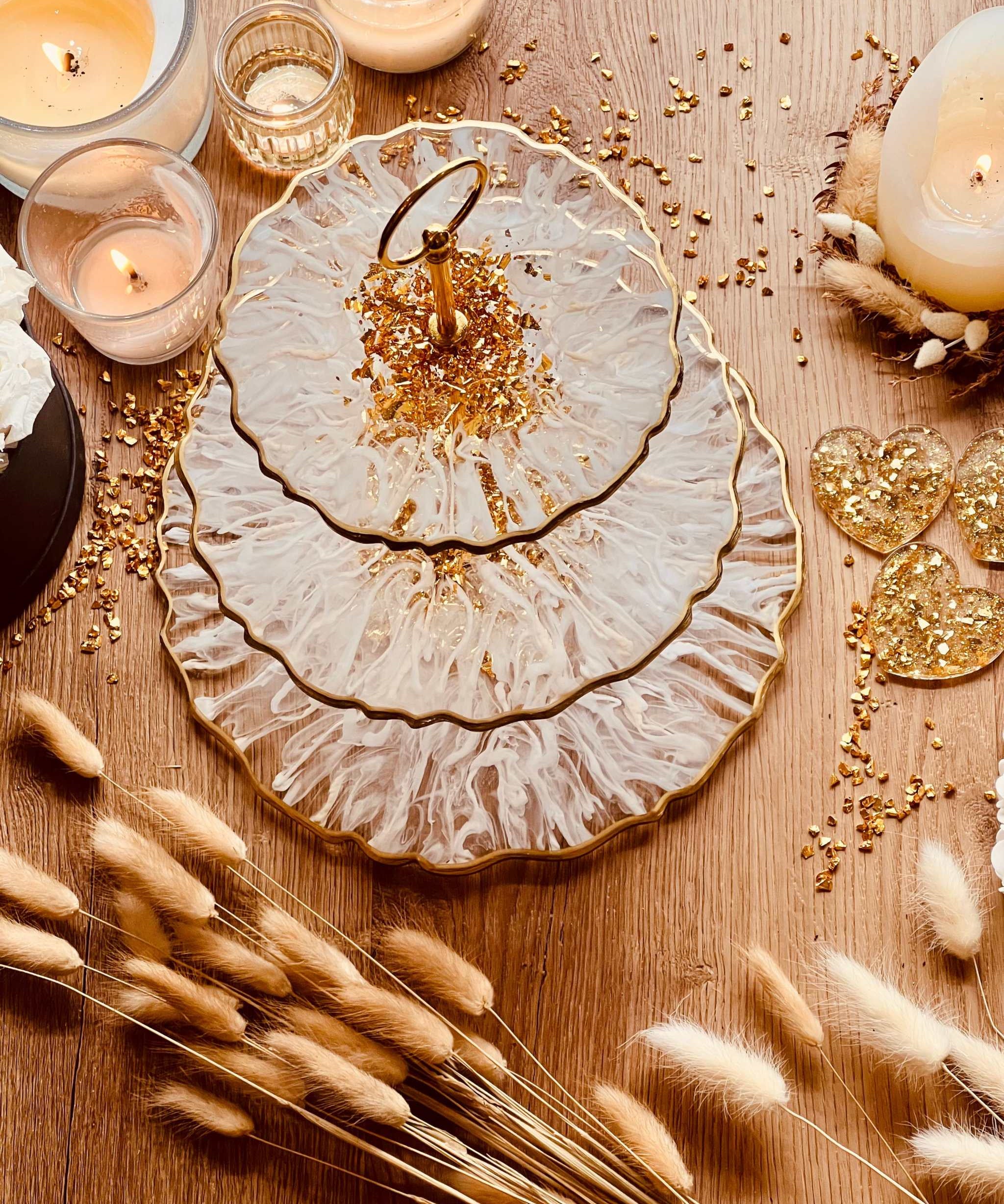 handgefertigte zweistufige Etagere aus Epoxidharz in Weiß-Gold mit 3D-Streifenmuster als elegantes Deko Set auf Holztisch mit Kerzen und Trockenblumen