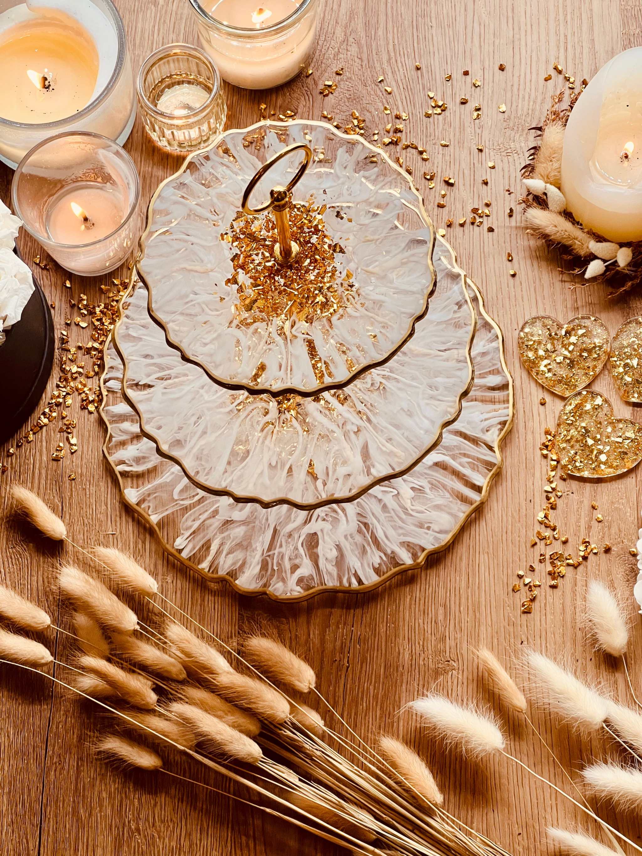 handgefertigte zweistufige Etagere aus Epoxidharz in Weiß-Gold mit 3D-Streifenmuster als elegantes Deko Set auf Holztisch mit Kerzen und Trockenblumen