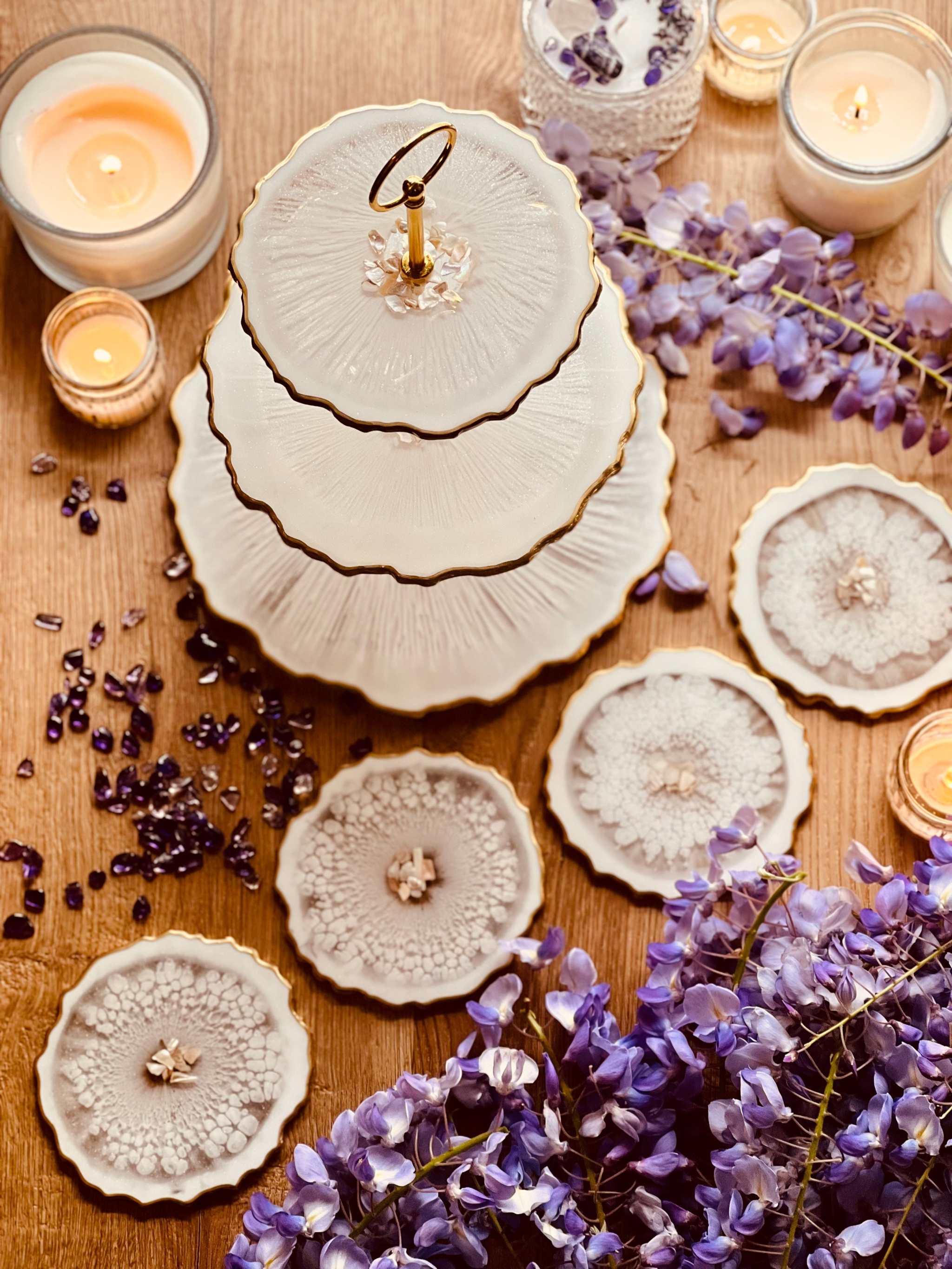 handgefertigte Deko Sets aus Resin mit unregelmäßigen, geschwungenen Ebenen in Beige und Weiß, dekoriert mit violetten Blumen und Kerzen auf Holzoberfläche