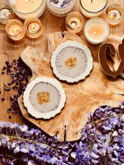 kunstvolle Untersetzer aus weiss-goldenem Resin handgemacht auf holztablett mit kerzen und lila blumen dekoriert