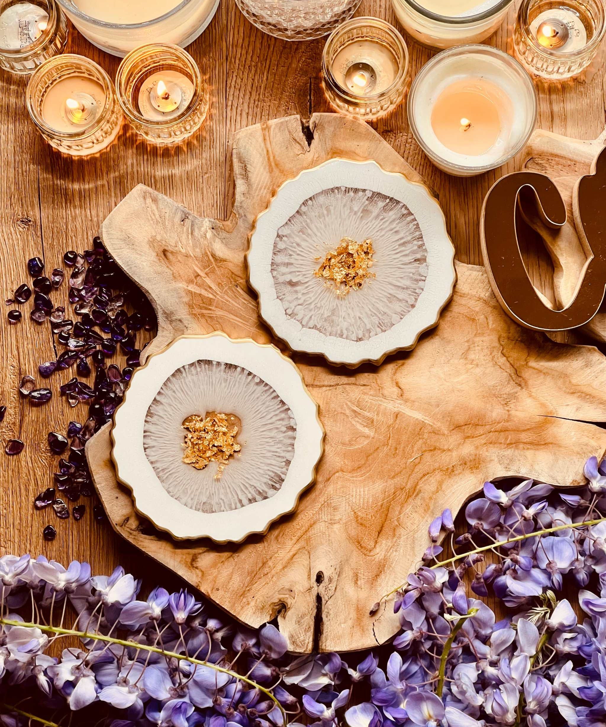 kunstvolle Untersetzer aus weiss-goldenem Resin handgemacht auf holztablett mit kerzen und lila blumen dekoriert