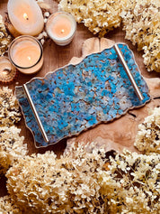 Handgemachtes Resin Tablett mit blauen Hortensien und silbernen Griffen auf Holzuntergrund mit Kerzen und Trockenblumen