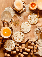 4 künstlerische Untersetzer aus weißem Resin mit goldenen Details auf Holztisch mit Kerzen und Weinkorken