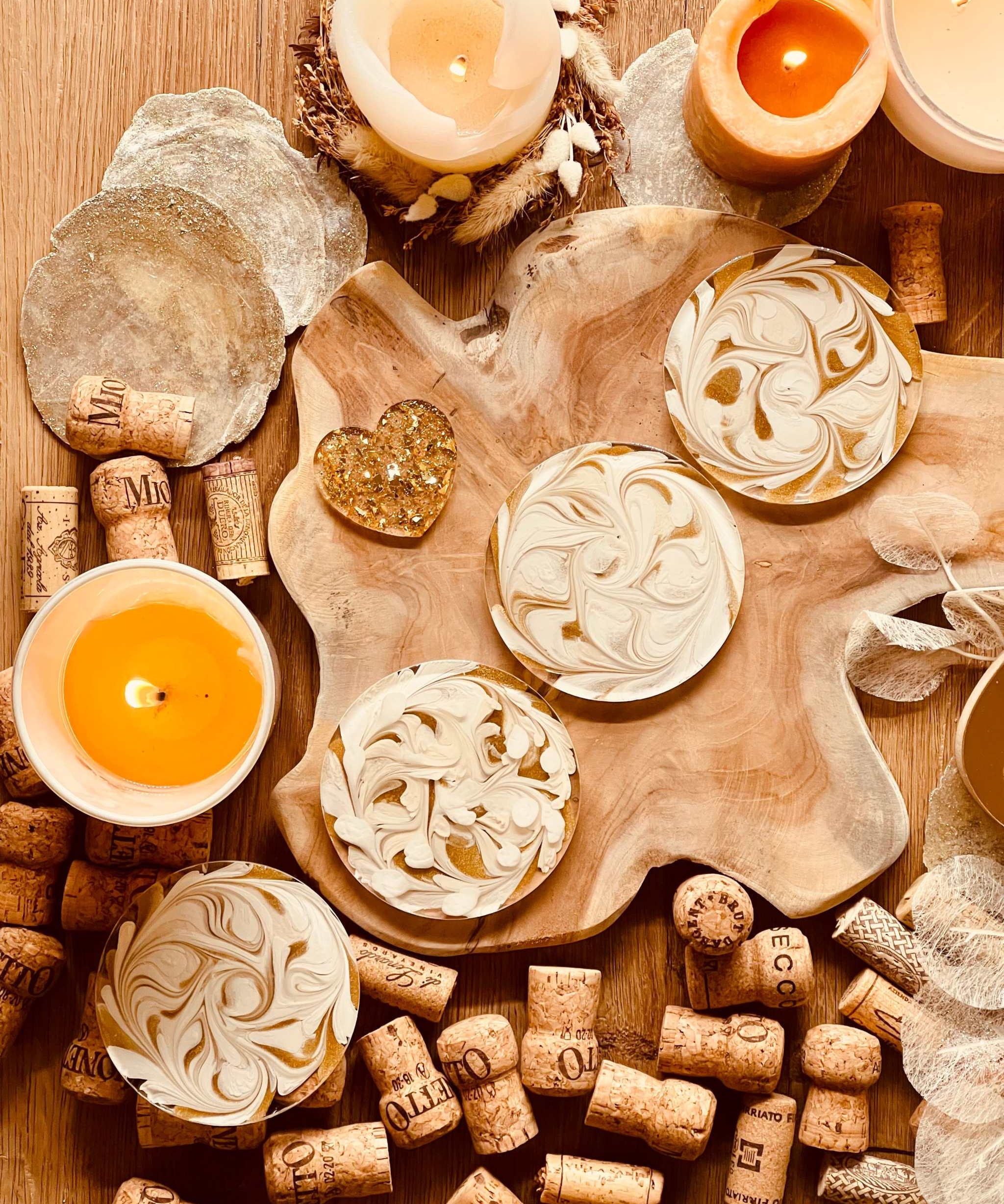 4 künstlerische Untersetzer aus weißem Resin mit goldenen Details auf Holztisch mit Kerzen und Weinkorken