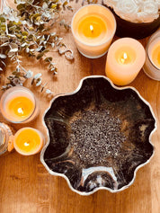 Handgemachte schwarze Schale aus Resin mit silbernen Details und unregelmäßigem Rand auf Holztisch mit brennenden Kerzen