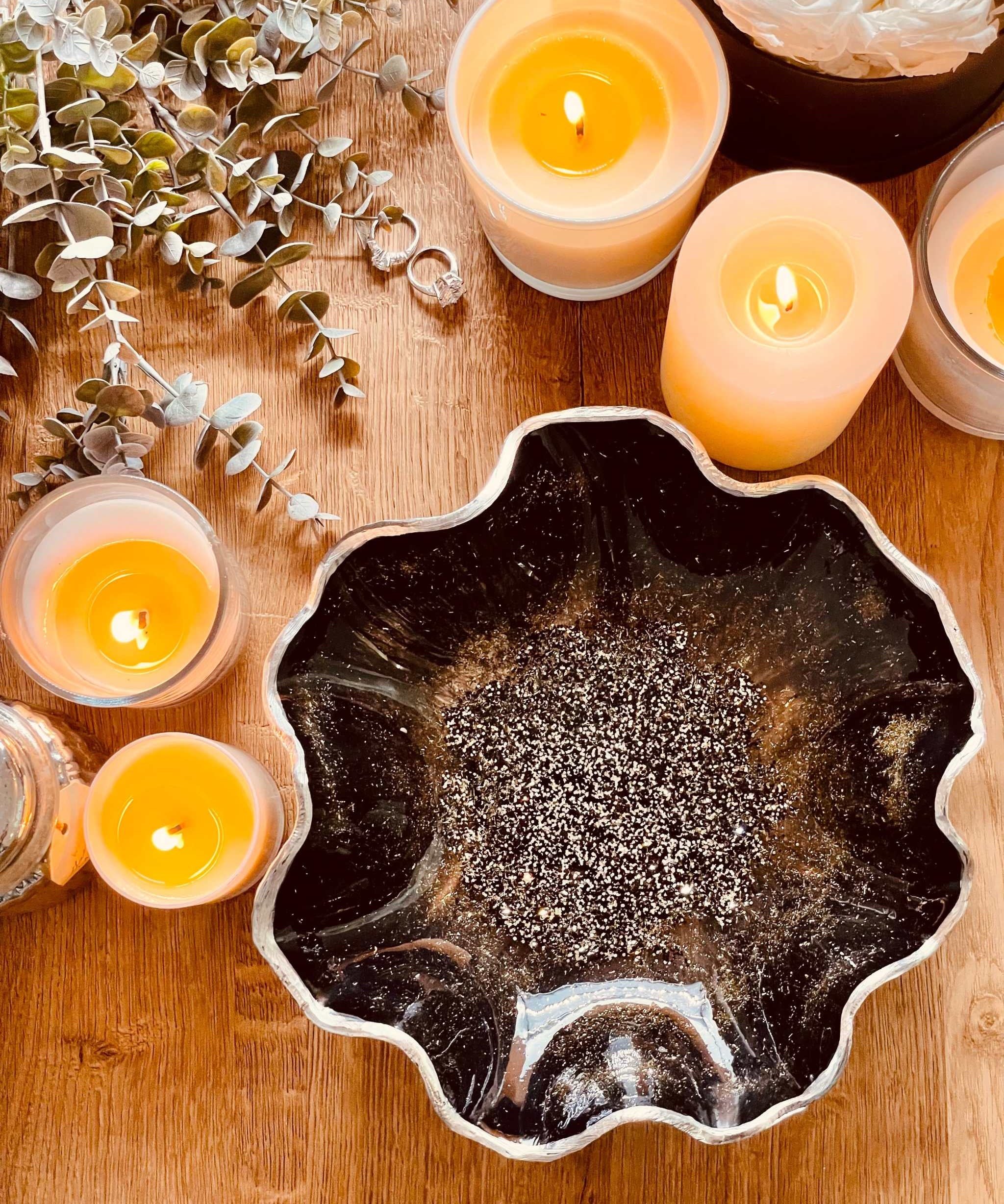 Handgemachte schwarze Schale aus Resin mit silbernen Details und unregelmäßigem Rand auf Holztisch mit brennenden Kerzen